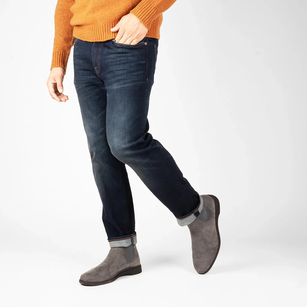 Person wearing blue jeans and gray boots on a white background