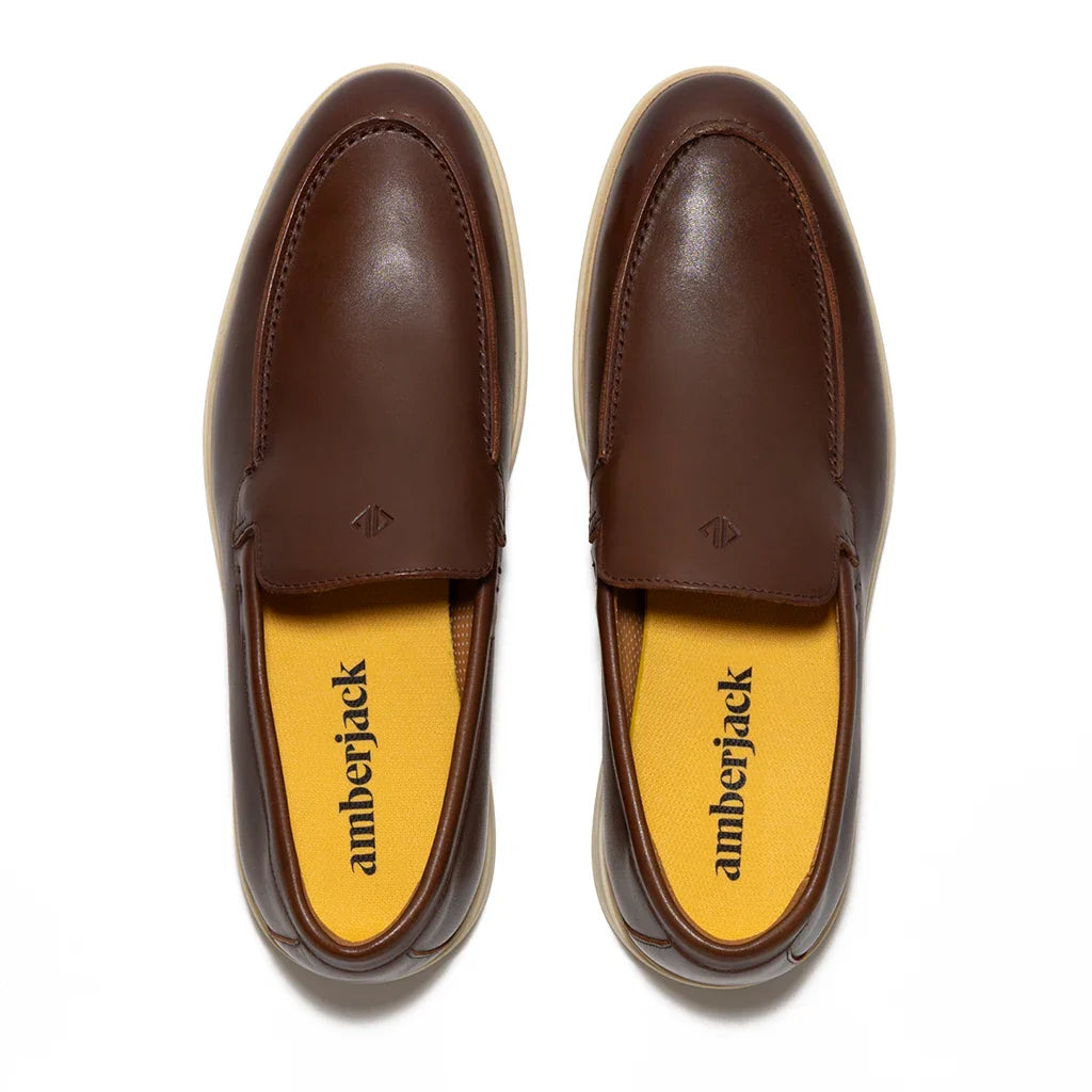 Pair of brown loafers with yellow soles on a white background