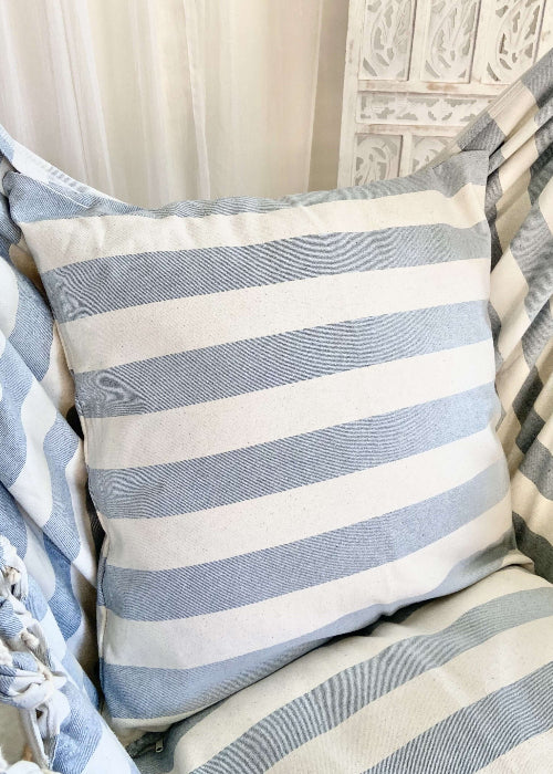 Striped blue and white pillow on a textured surface
