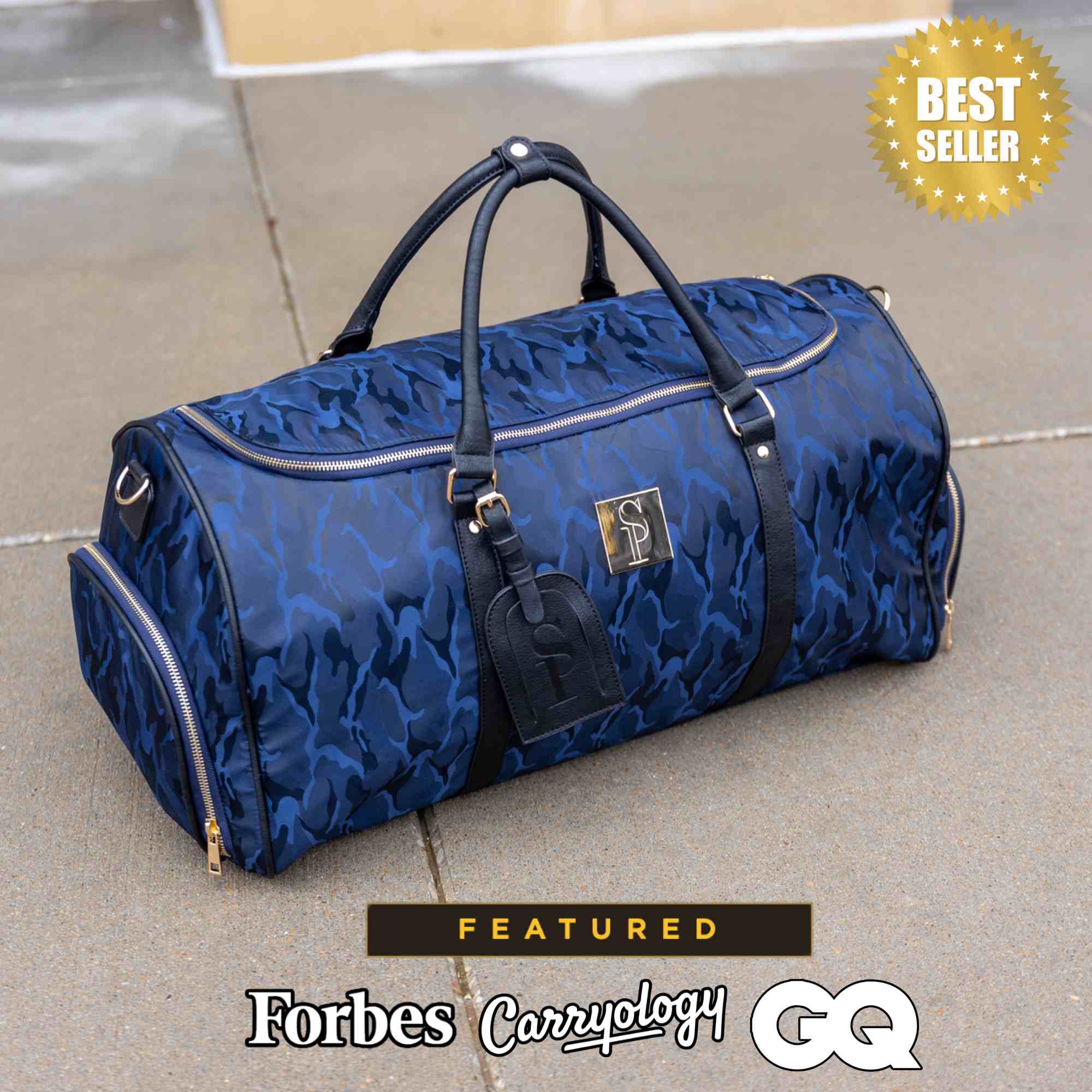 Blue duffel bag with black handles and trim on a concrete surface, featuring 'Forbes Carzyology' and 'GQ'.