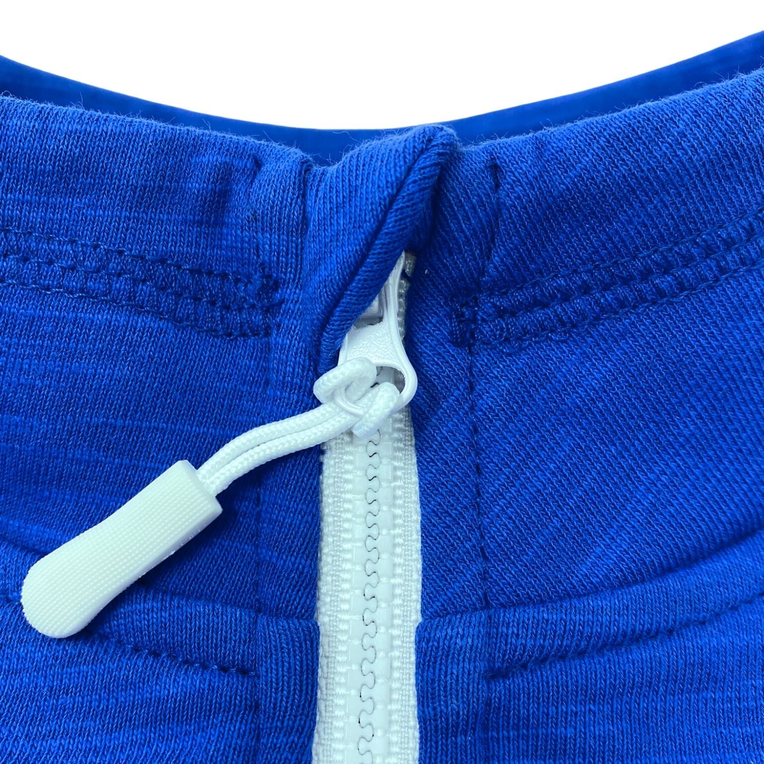 Close-up of a blue jacket with a white zipper and pull tab on a white background