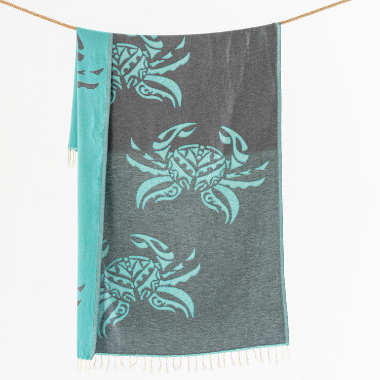 Gray towel with teal crab patterns hanging on a line