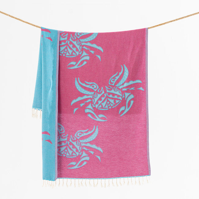 Pink towel with blue crab patterns hanging on a line