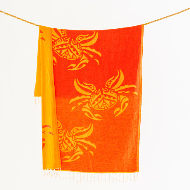 Orange towel with yellow crab patterns hanging on a line