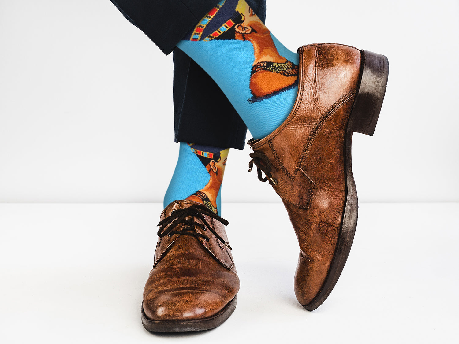 Brown leather shoes with colorful socks featuring animal designs on a white background