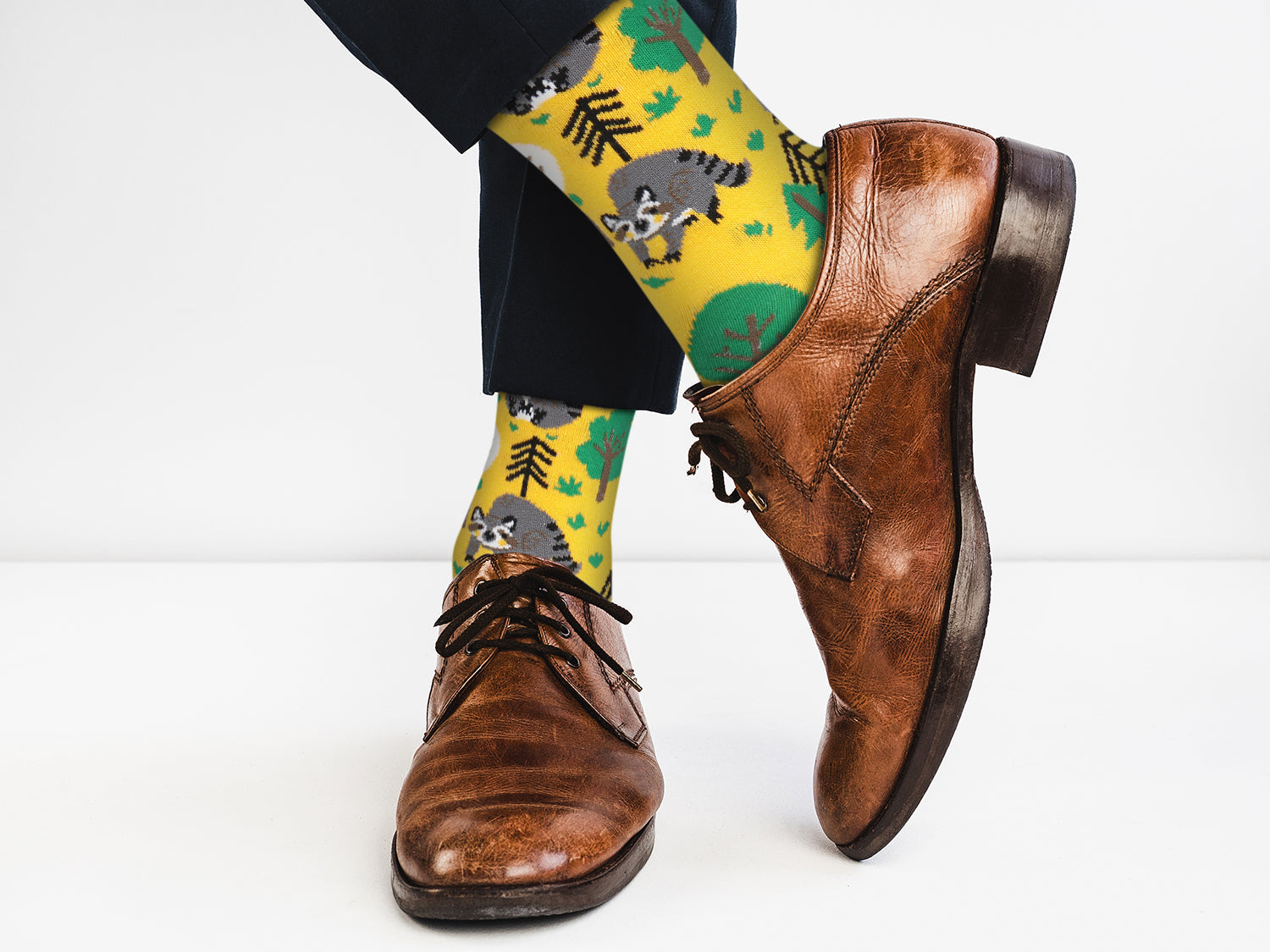 Brown dress shoes and yellow socks with raccoon design on a white background