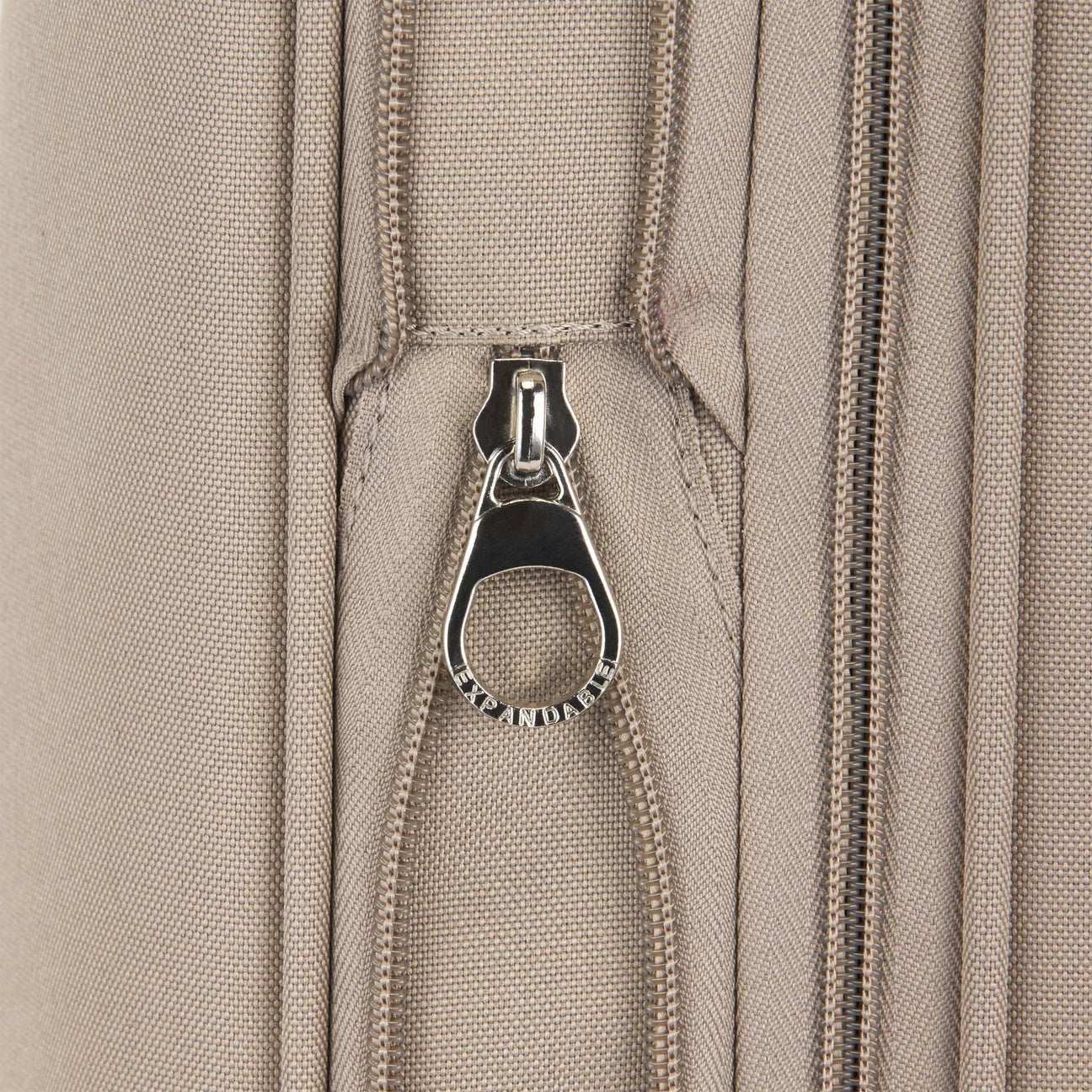 Close-up of a beige fabric with a zipper and metal zipper pull.