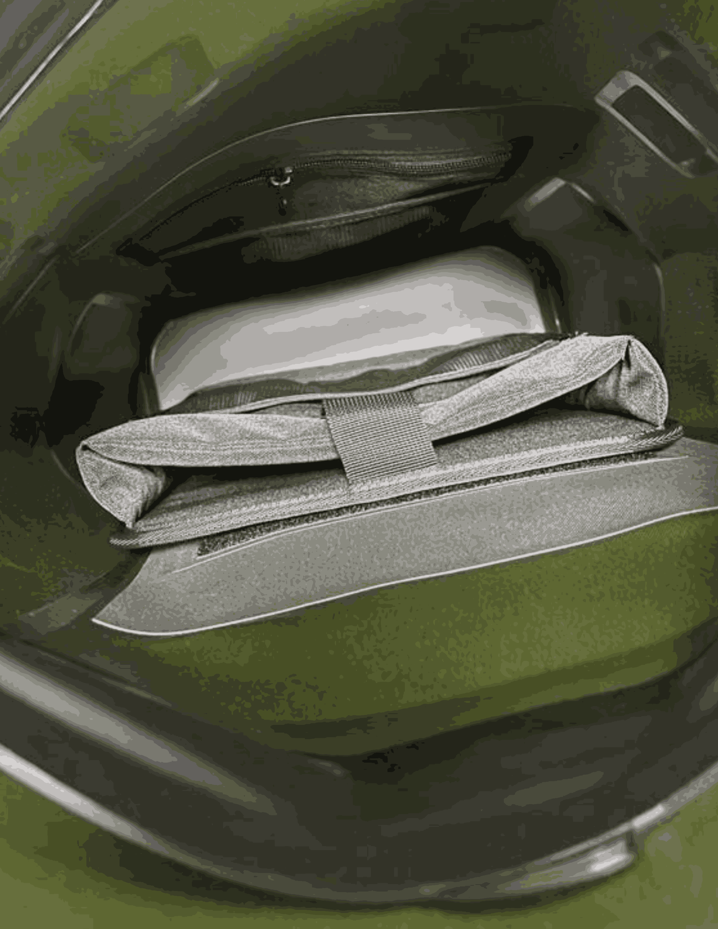 Green vehicle with a folded gray blanket inside the open trunk.