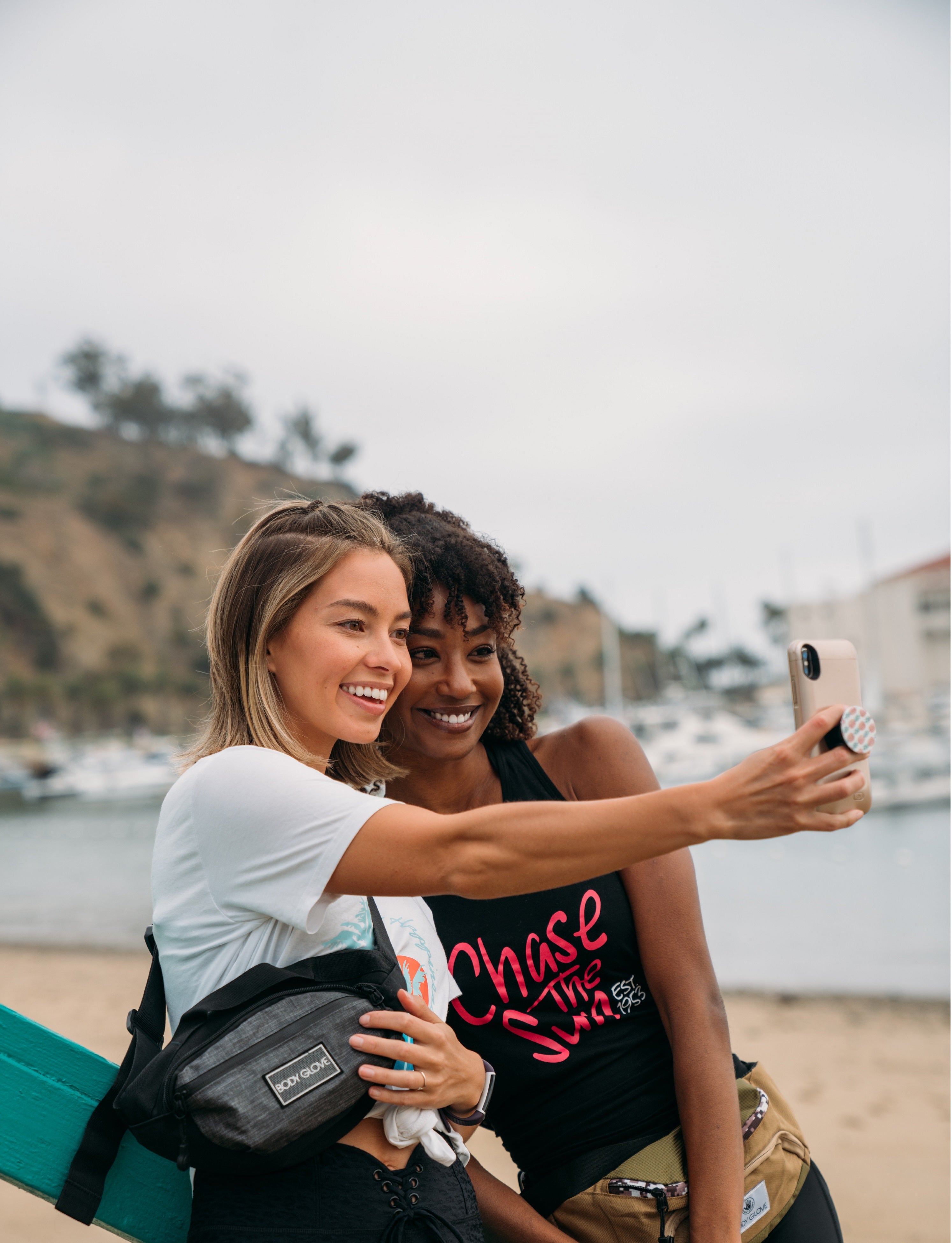 Two women taking a selfie on a beach with a scenic background