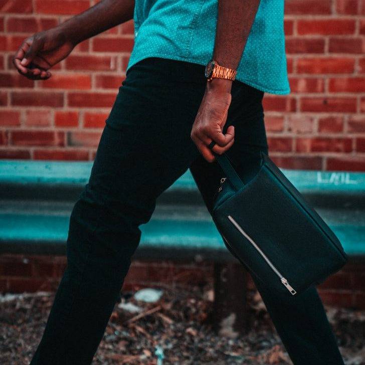 Person holding a black bag against a brick wall background