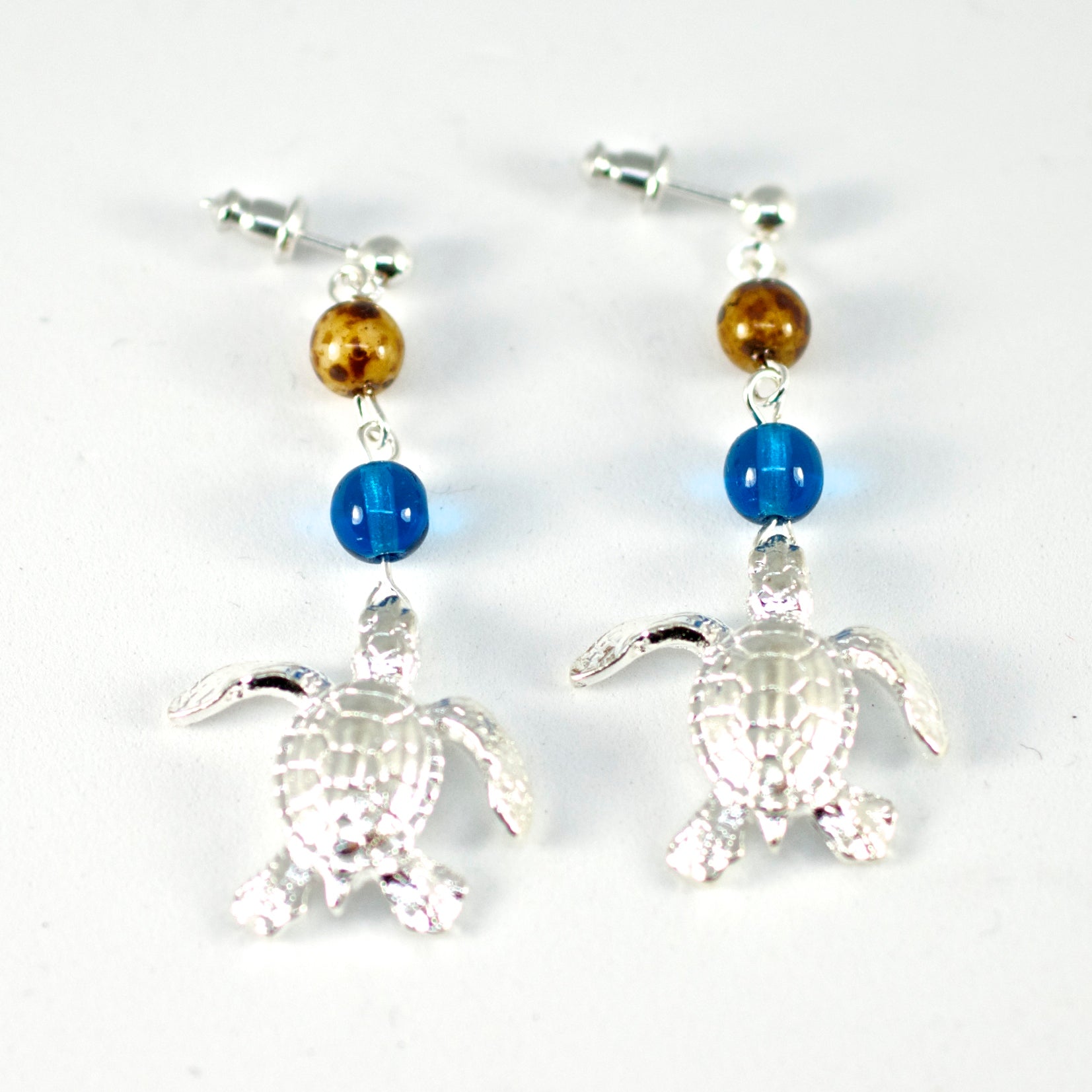 Turtle-shaped earrings with blue and gold beads on a white background