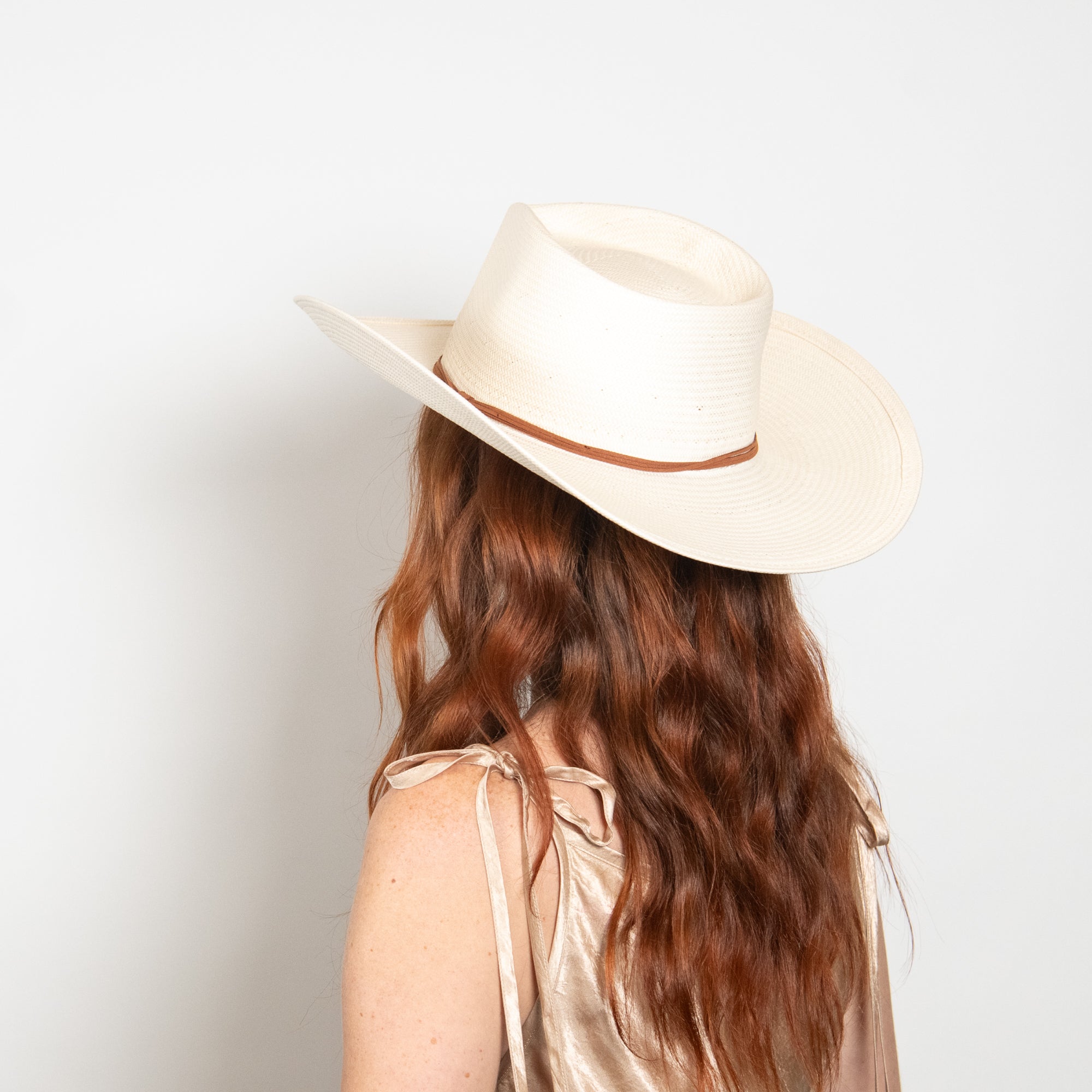 Person wearing a beige cowboy hat with a white background