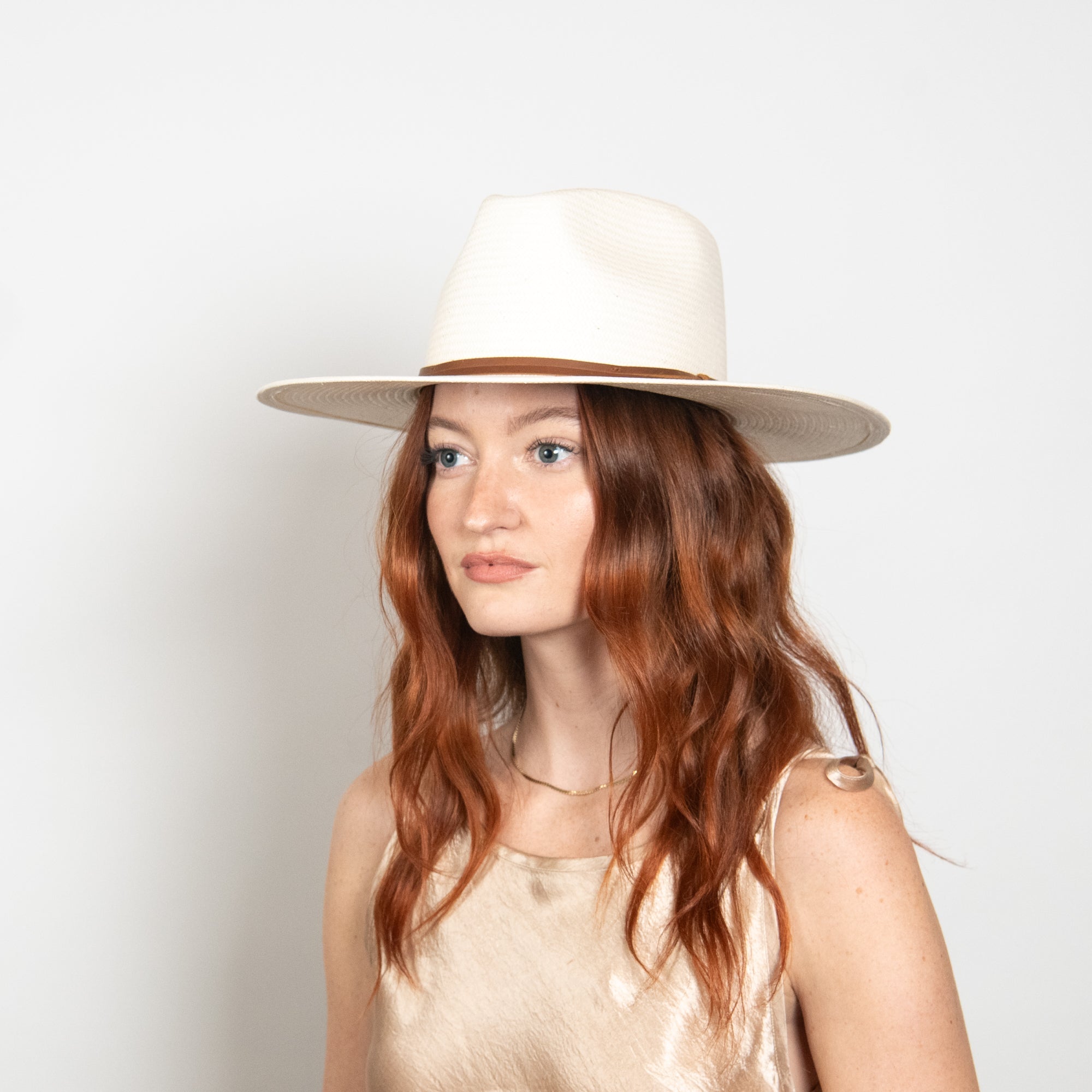 Woman wearing a white hat against a light background