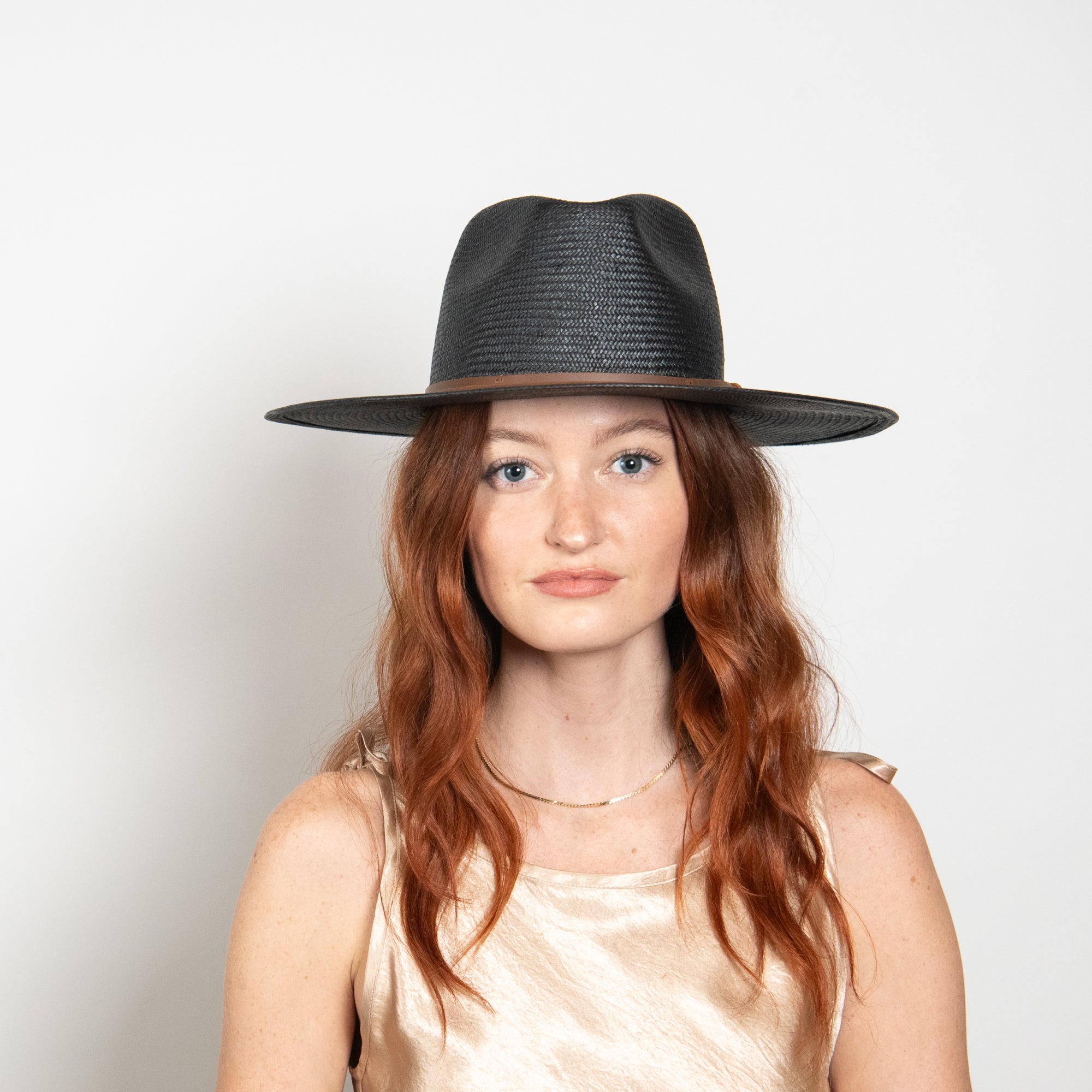 Woman wearing a black fedora hat against a white background