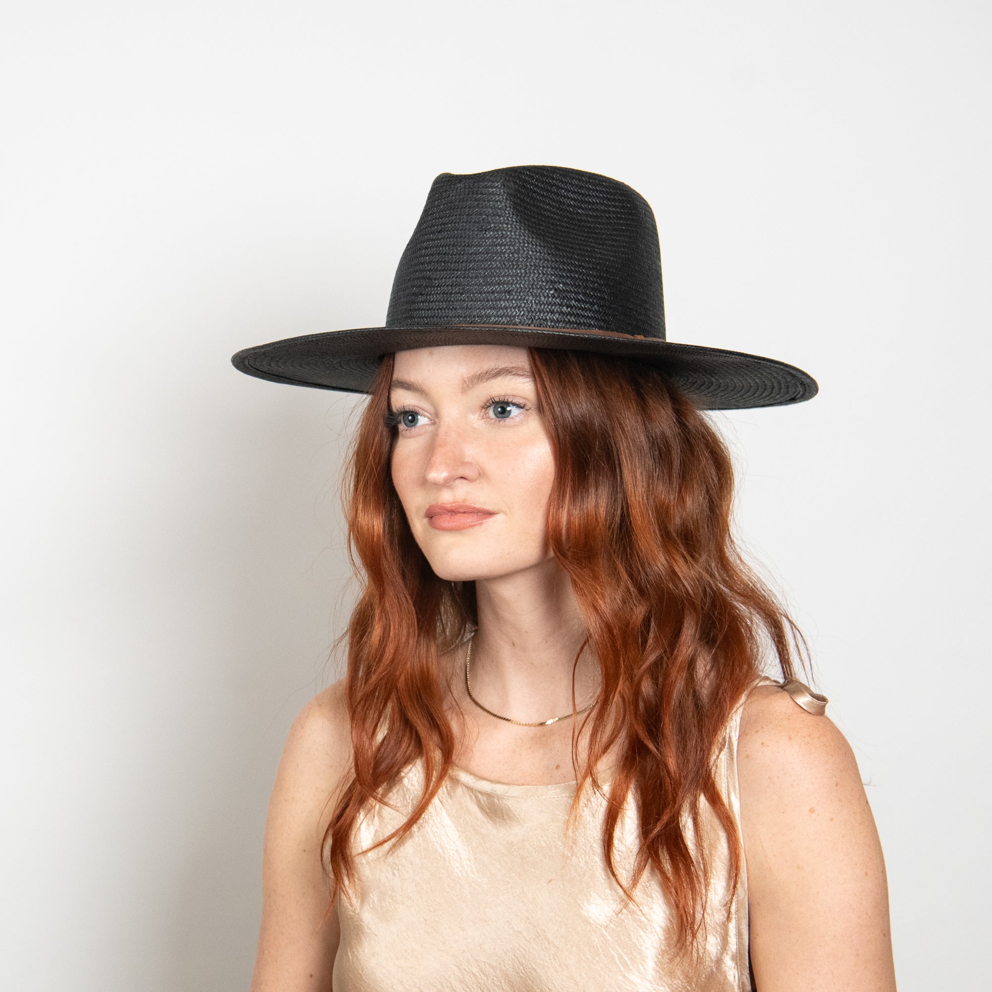 Woman wearing a black hat against a plain background