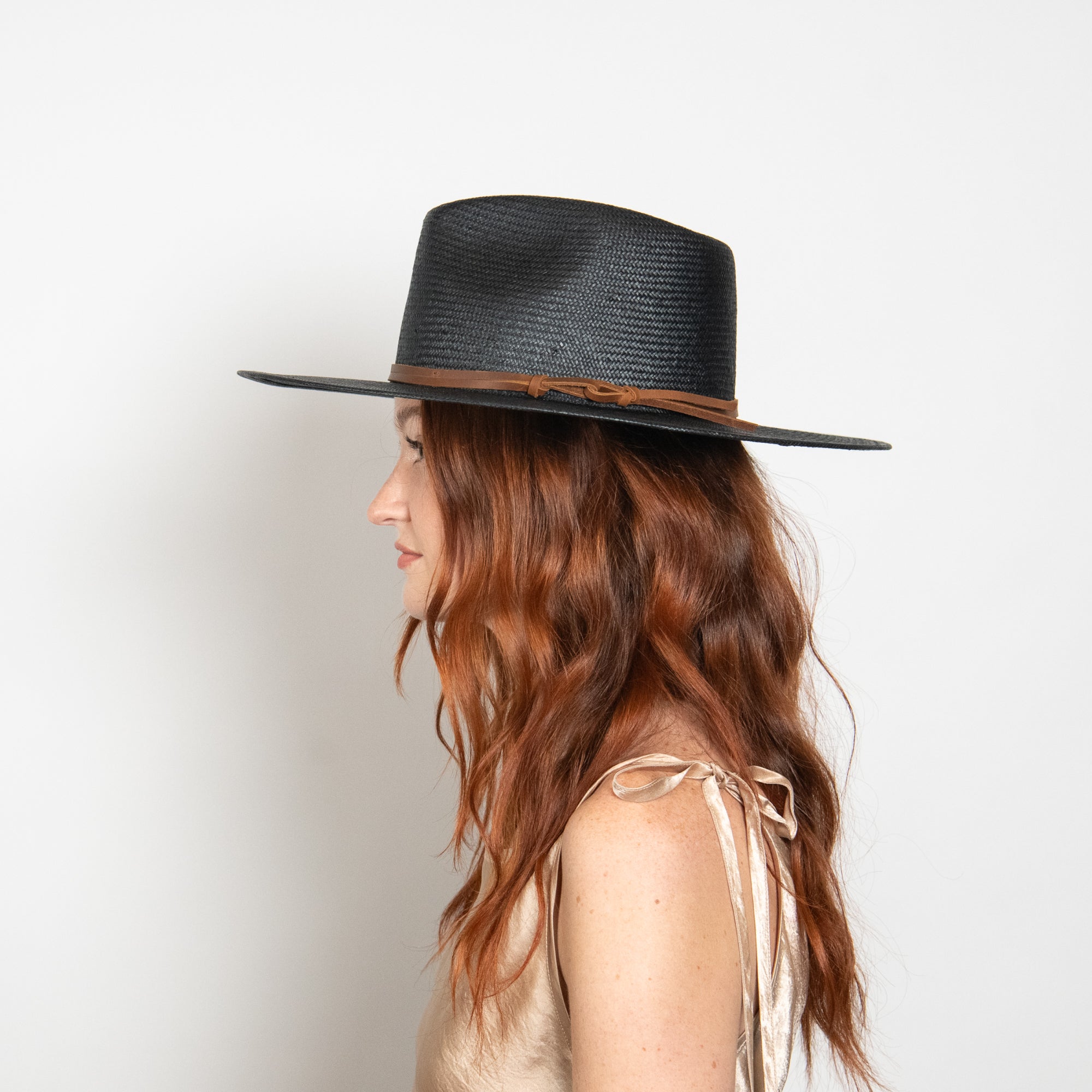 Woman wearing a black hat with a brown band on a white background