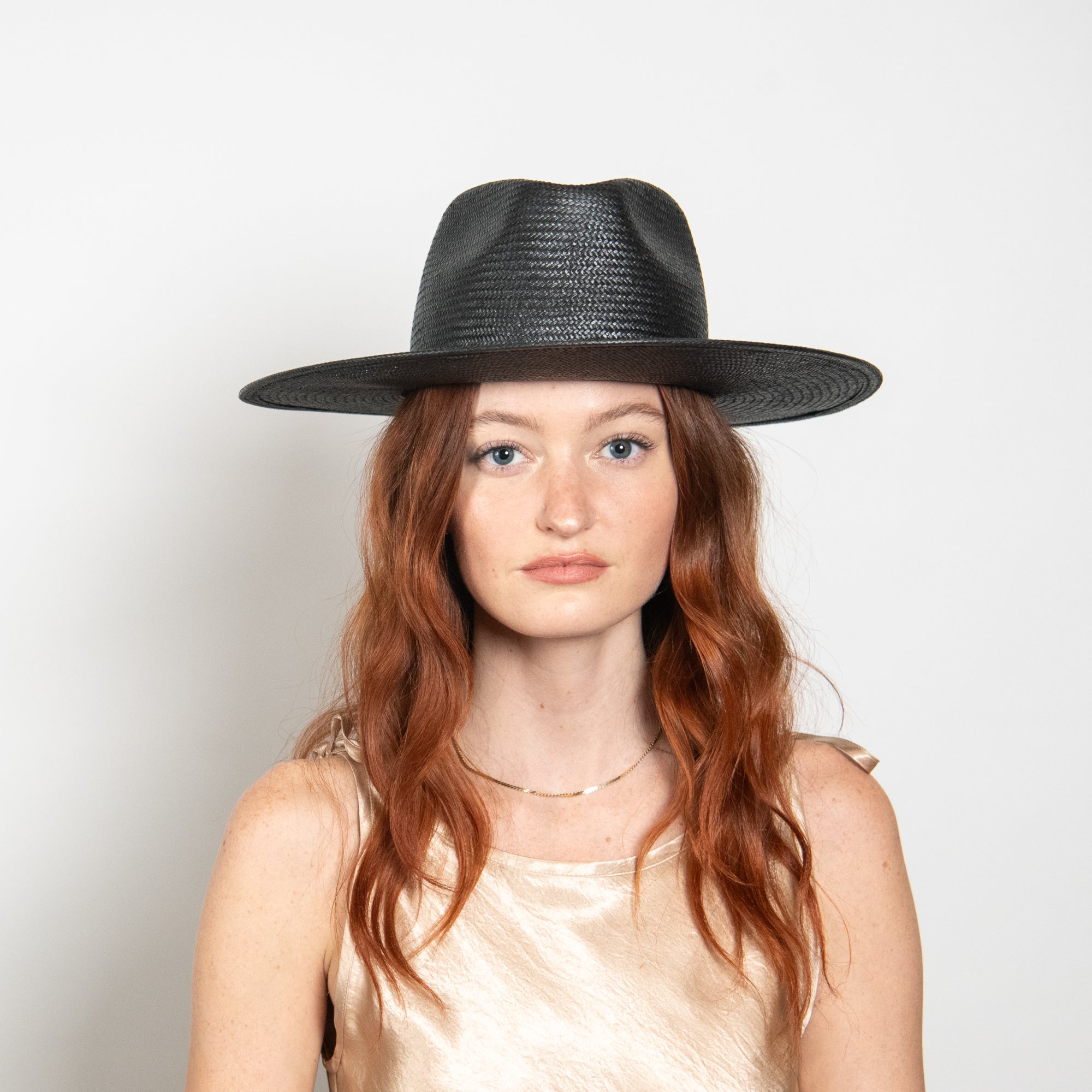 Woman wearing a black hat against a plain background