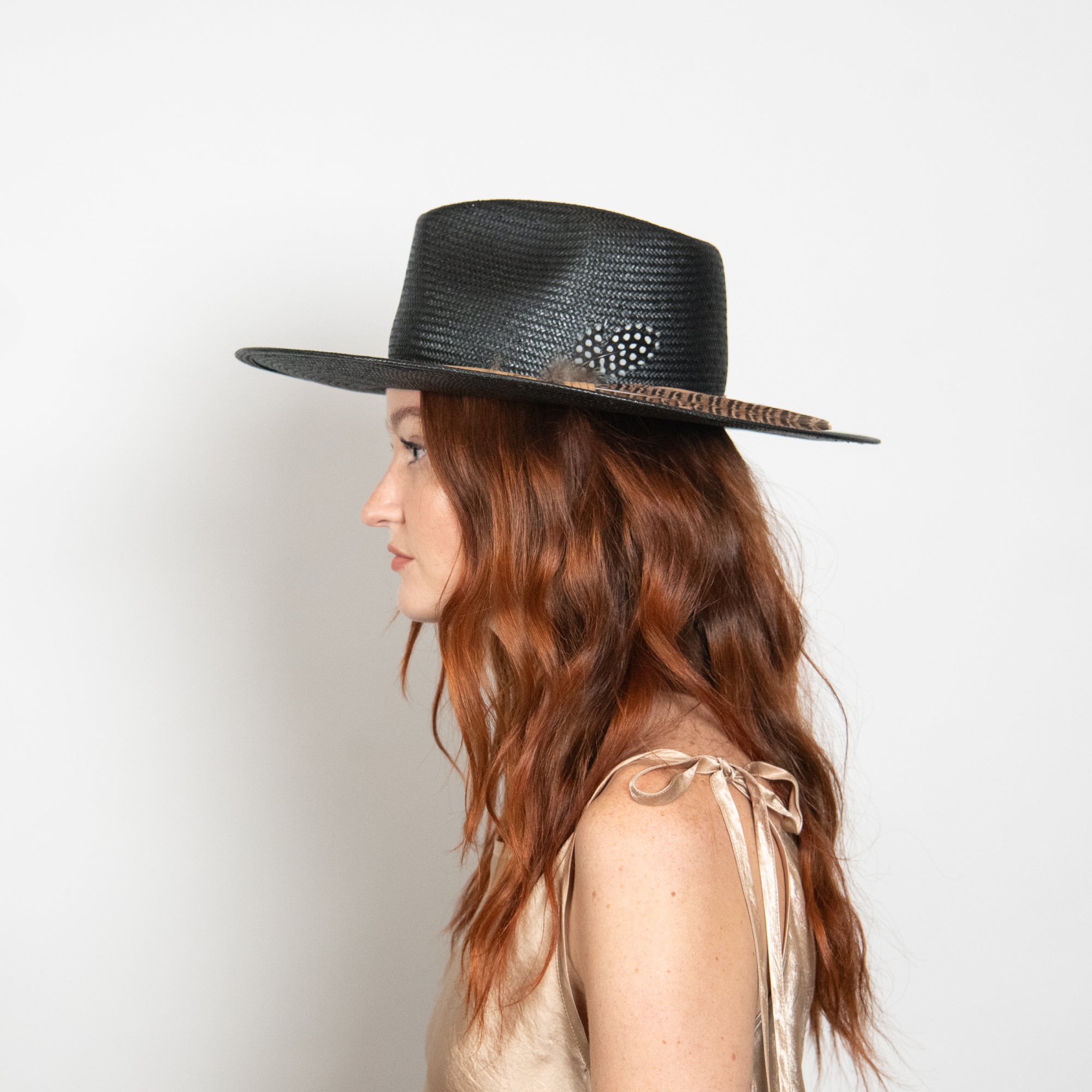 Woman wearing a black straw hat with a decorative band on a white background