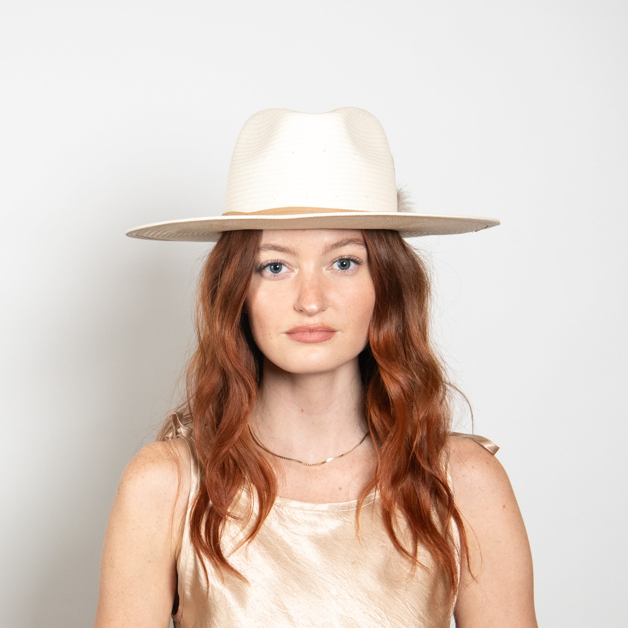 Woman wearing a white hat against a plain background