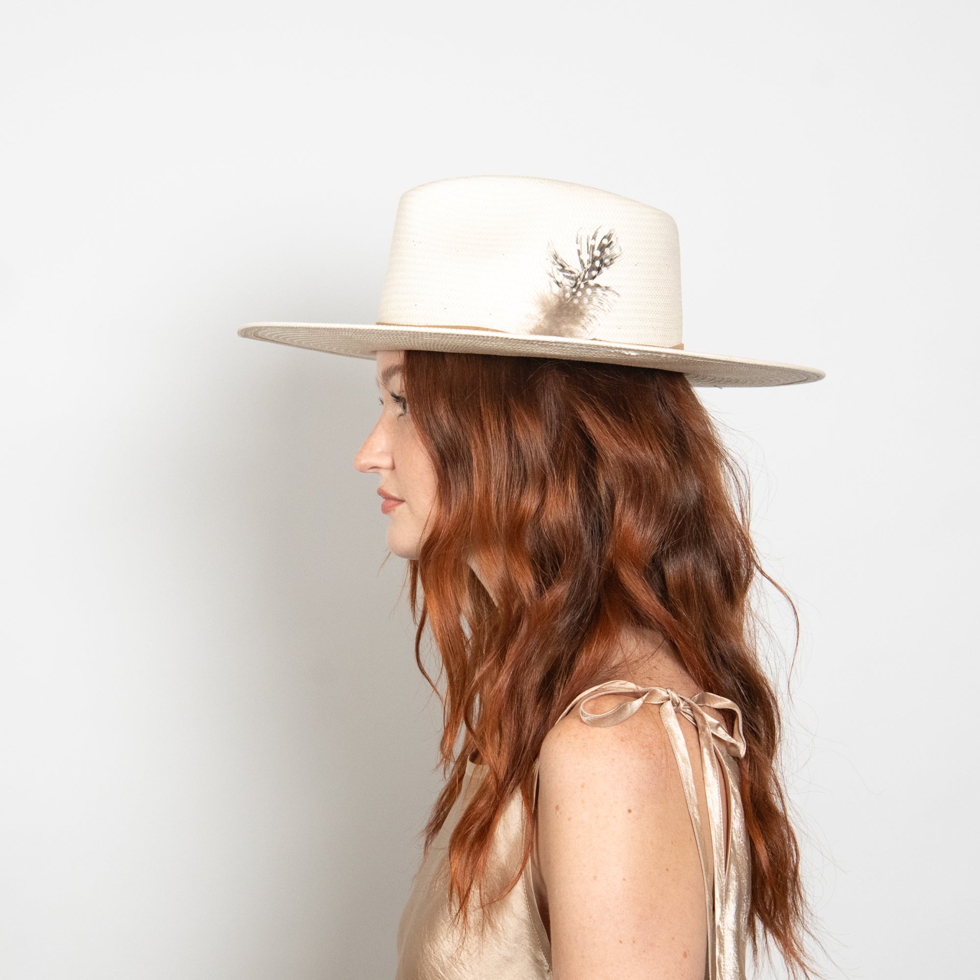 Woman wearing a white hat with a deer emblem on a light gray background