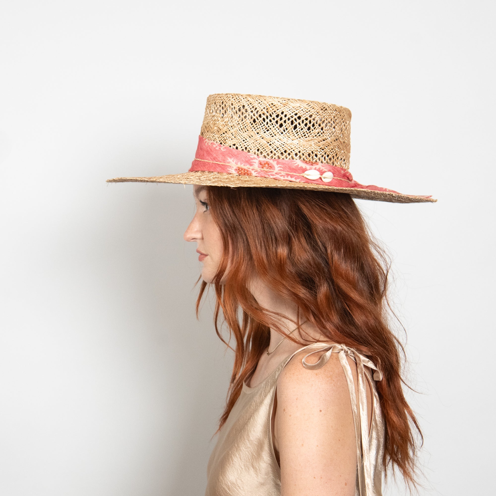 Woman wearing a straw hat with a red band on a light gray background