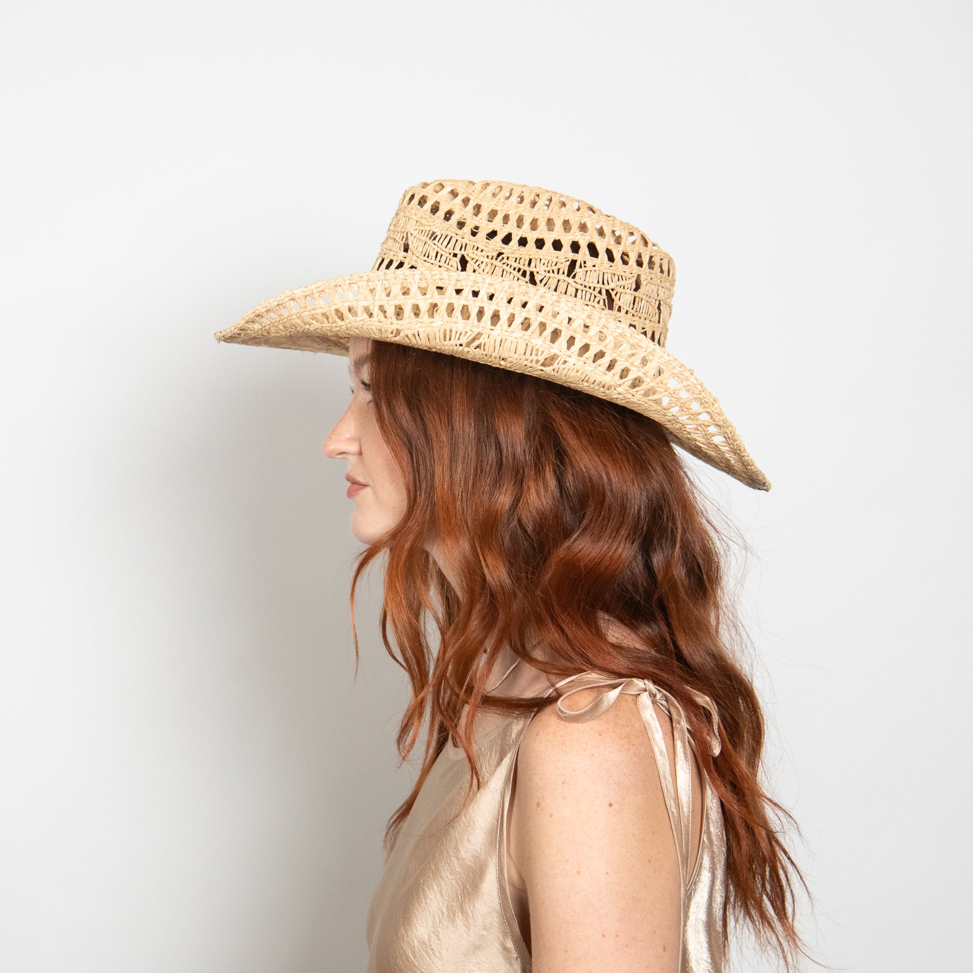 Woman wearing a straw hat against a plain background