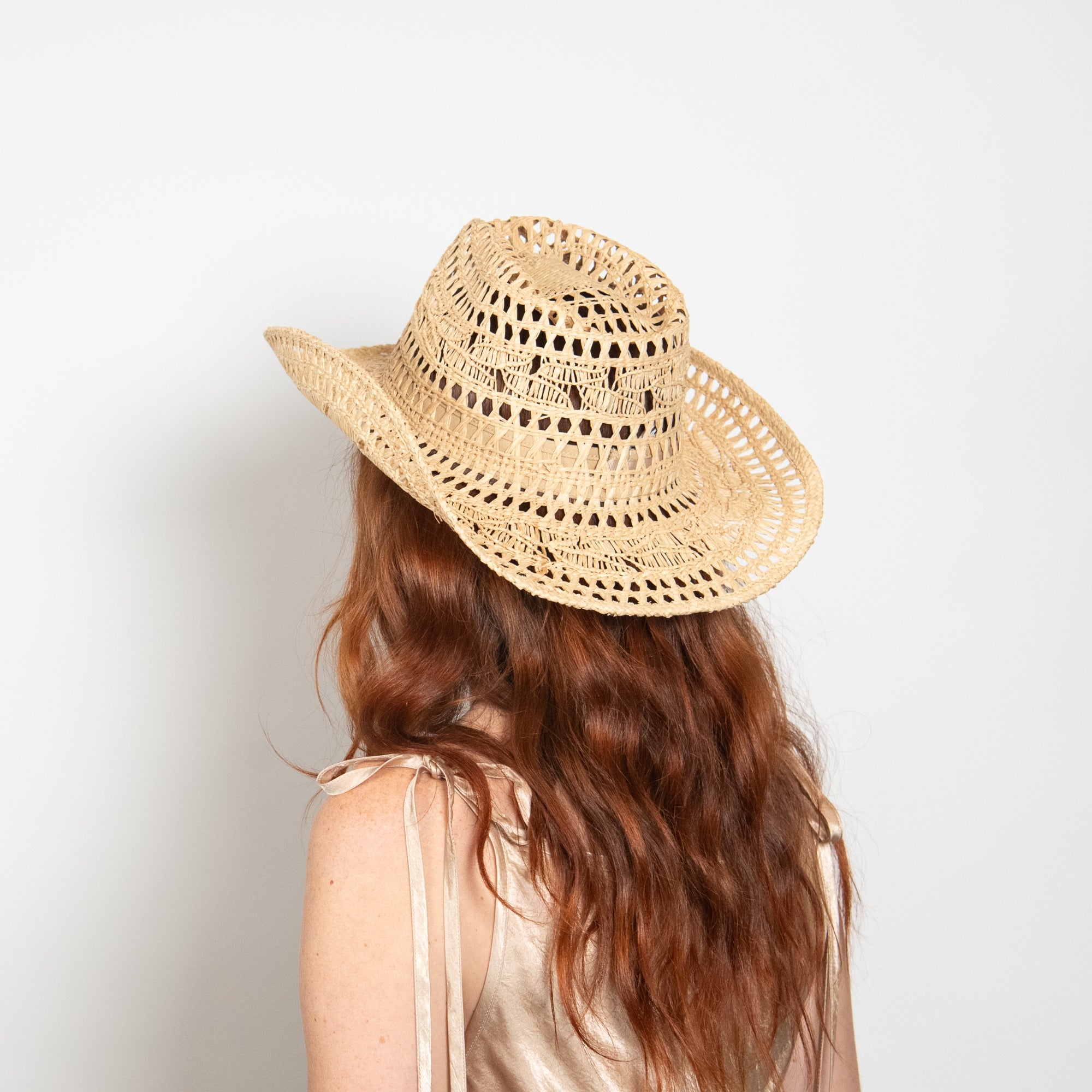 Person wearing a straw hat on a plain background