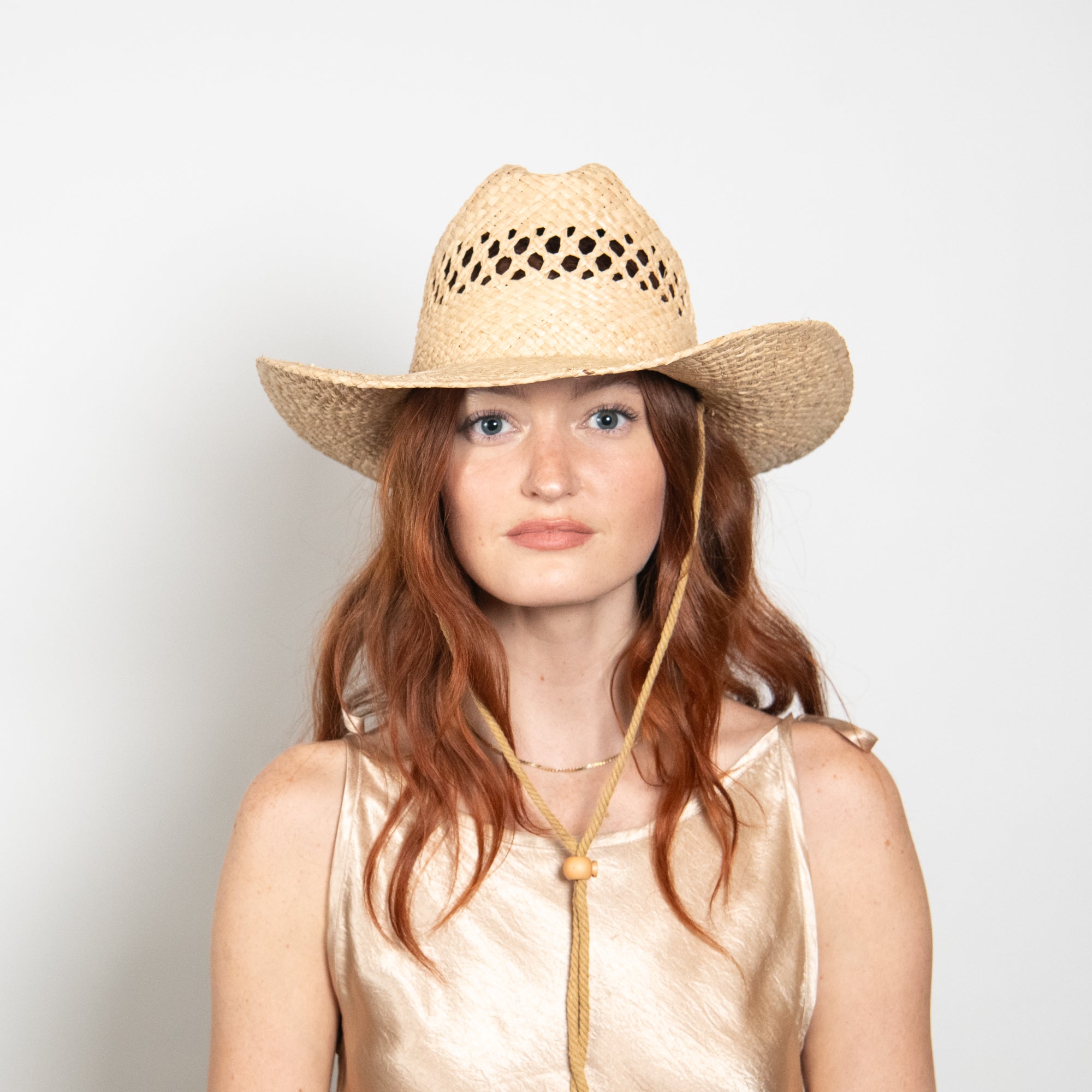 Woman wearing a straw cowboy hat on a plain background