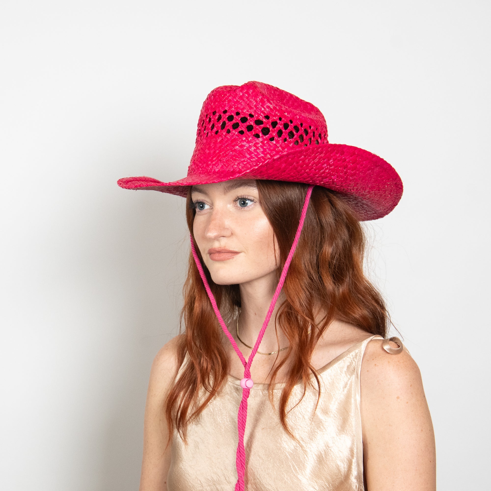 Woman wearing a pink straw hat with a white background