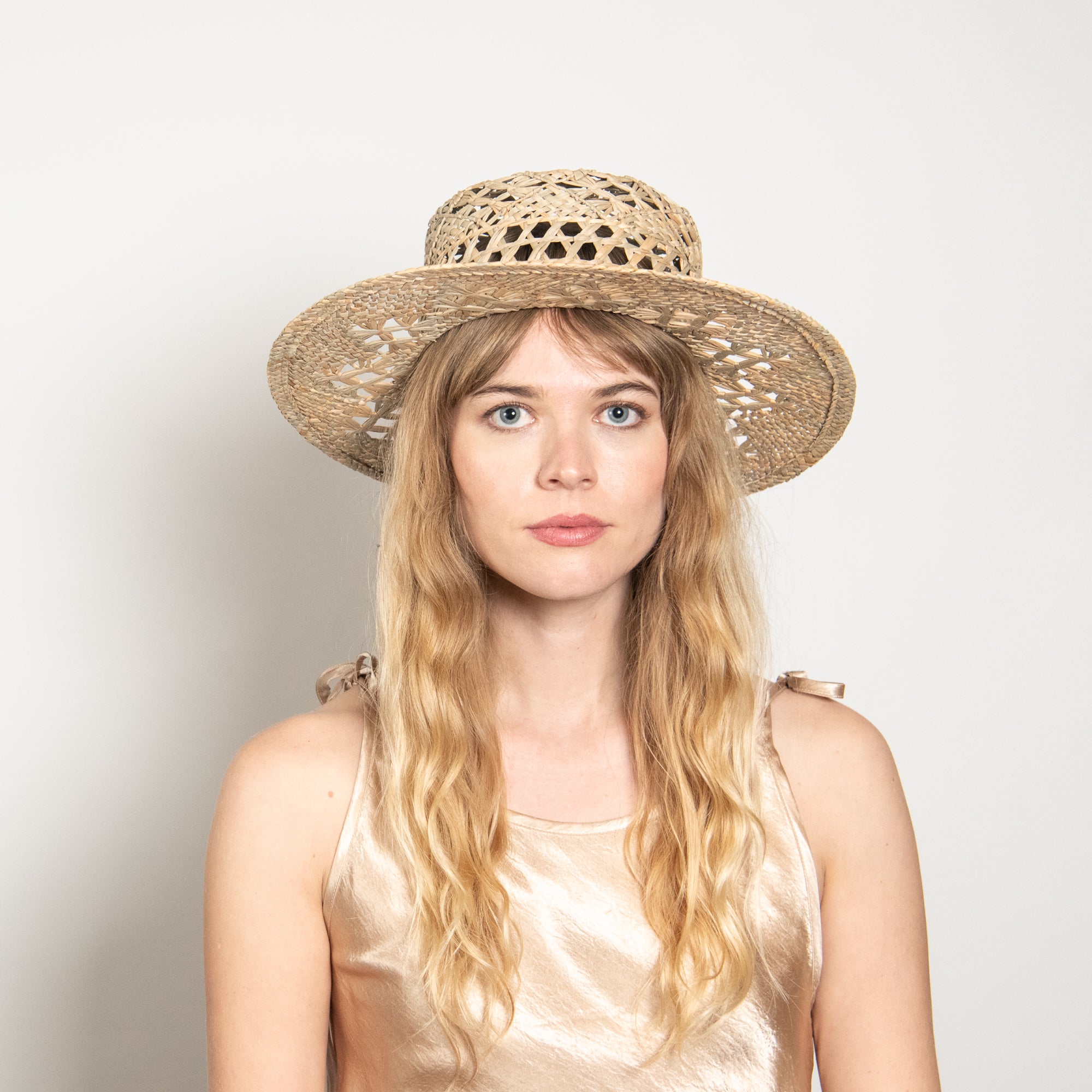 Woman wearing a straw hat against a plain background