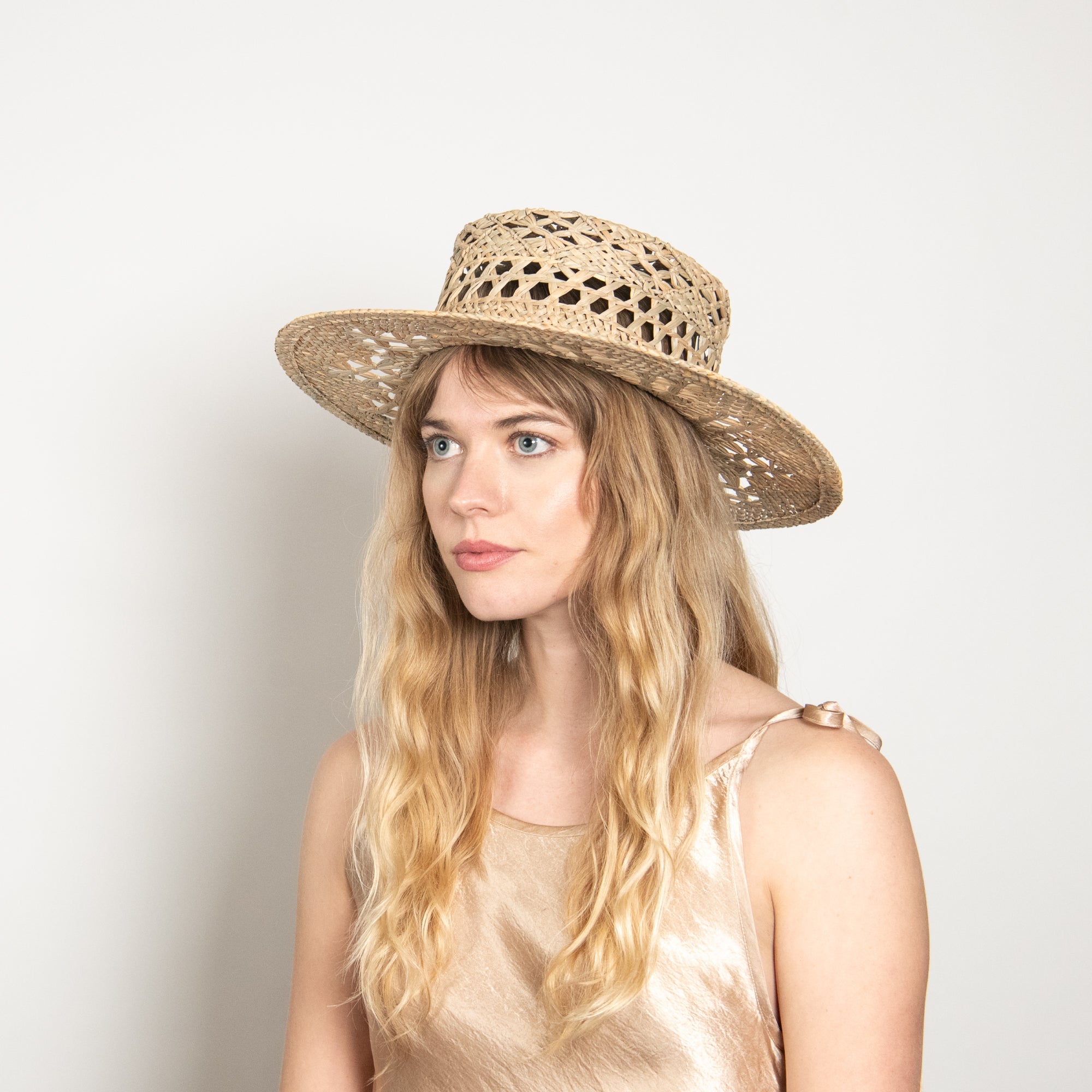 Woman wearing a straw hat against a plain background