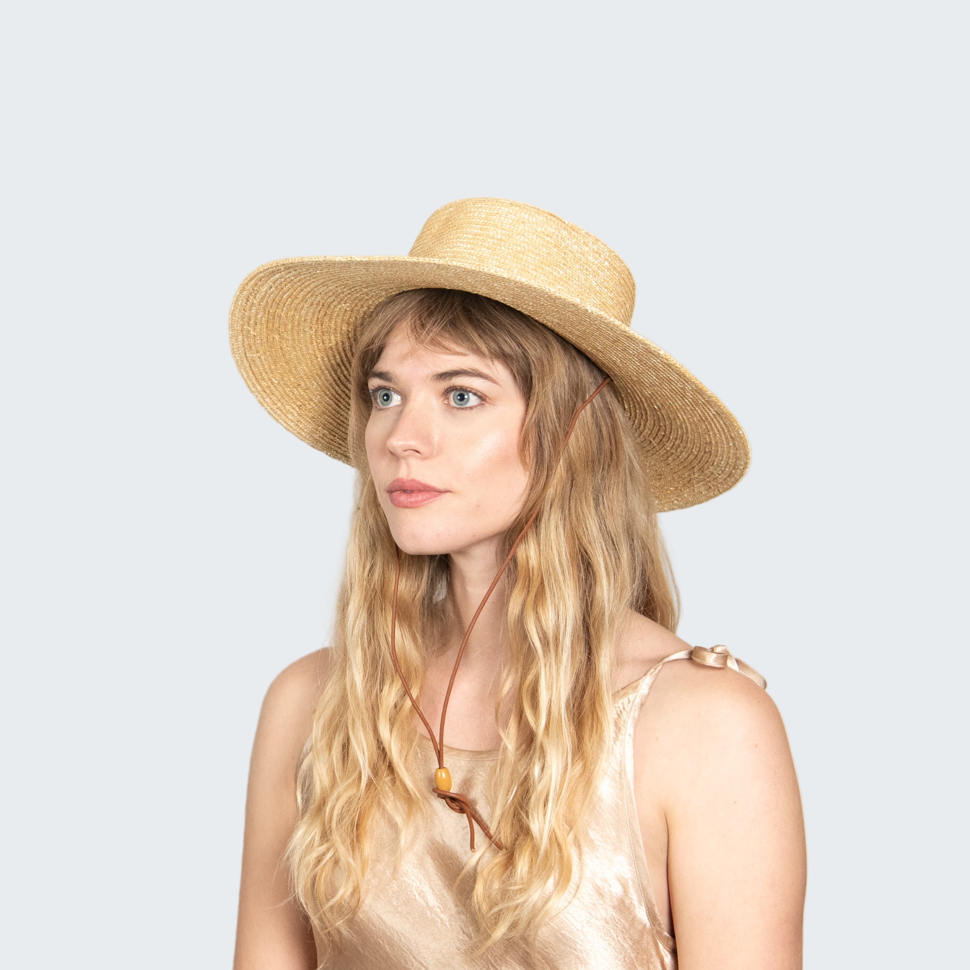 Woman wearing a straw hat against a plain background