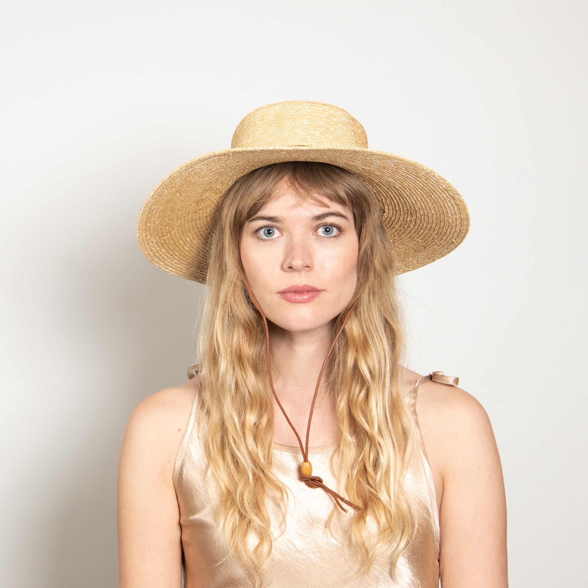 Woman wearing a straw hat against a plain background