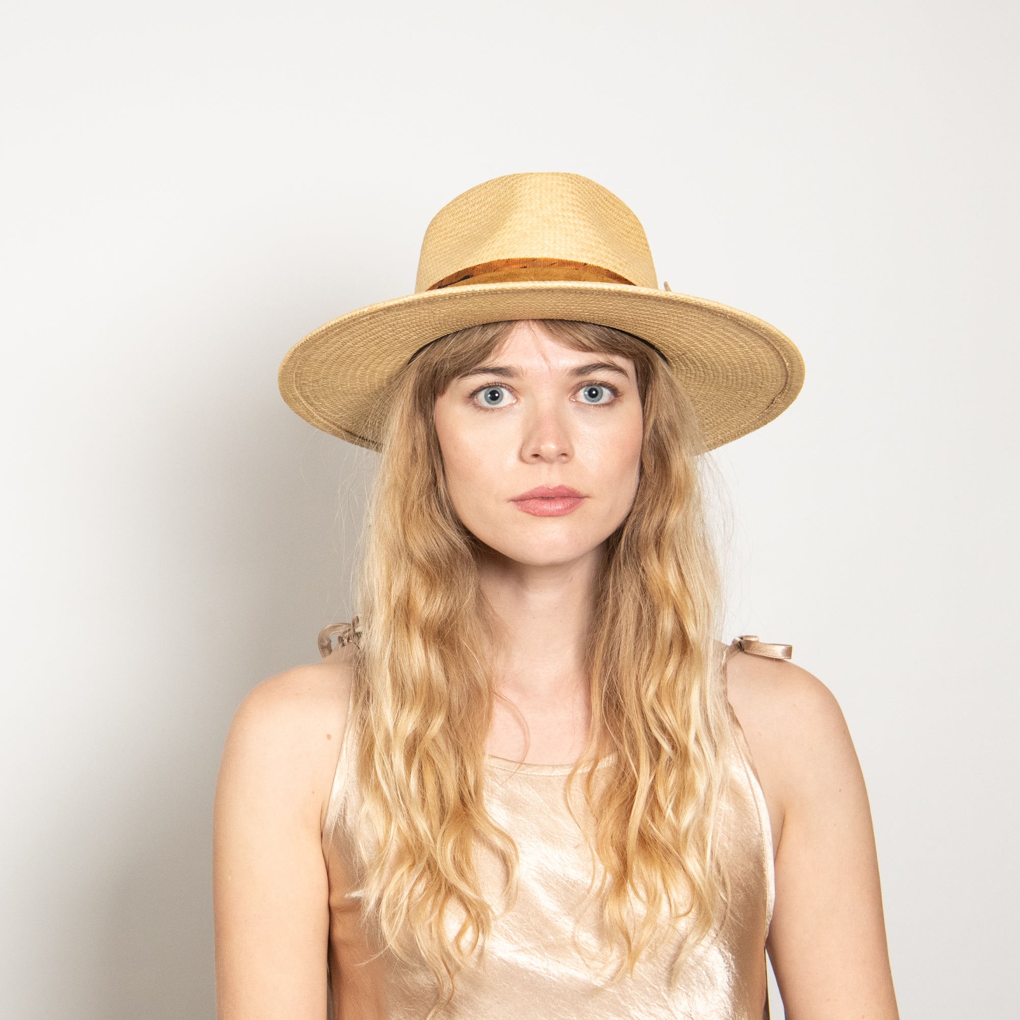 Woman wearing a straw hat against a plain background
