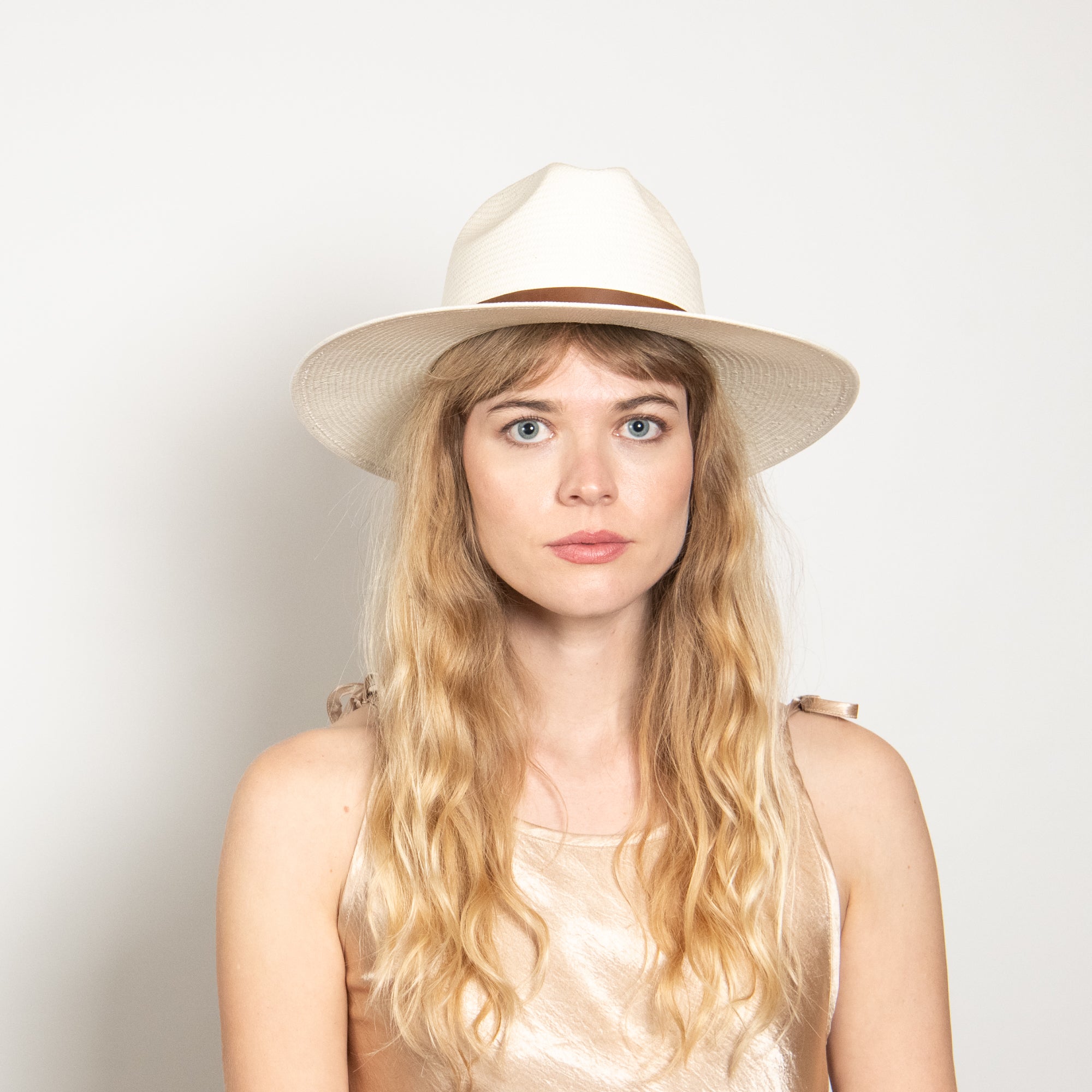 Woman wearing a white hat against a plain background