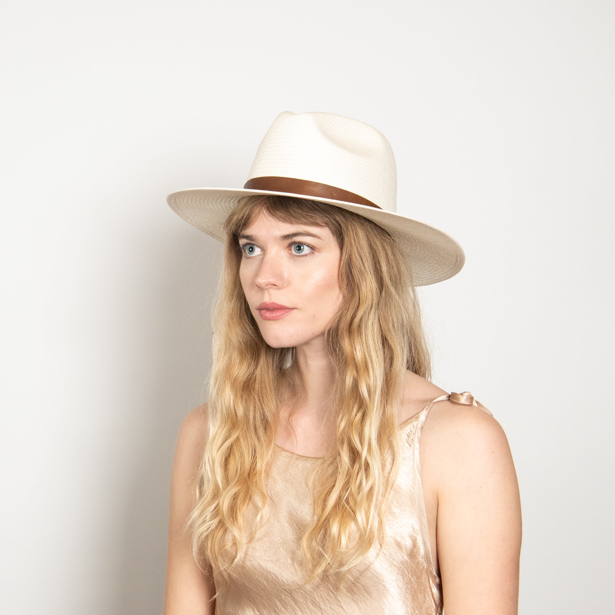 Woman wearing a beige hat against a plain background