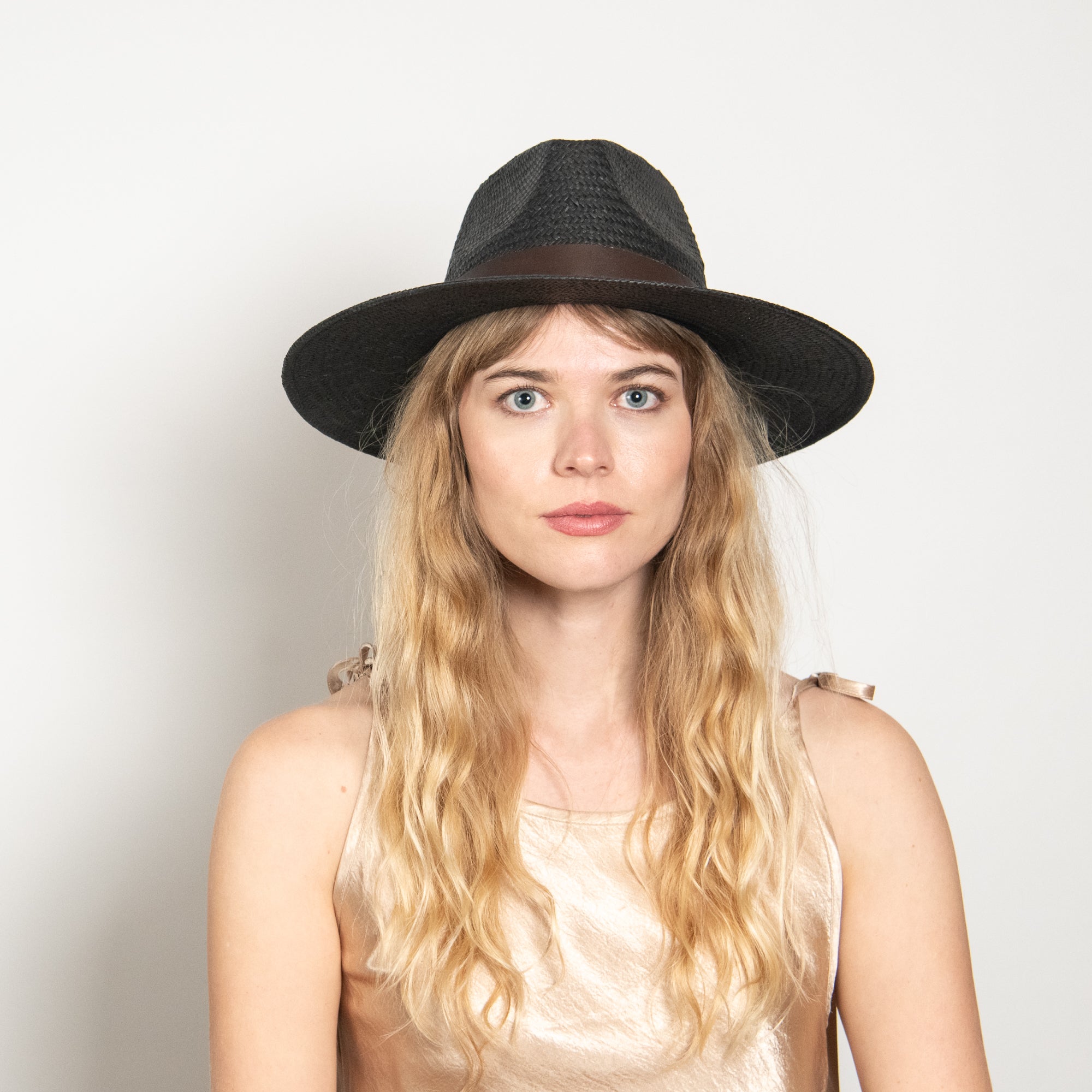 Woman wearing a black hat against a plain background