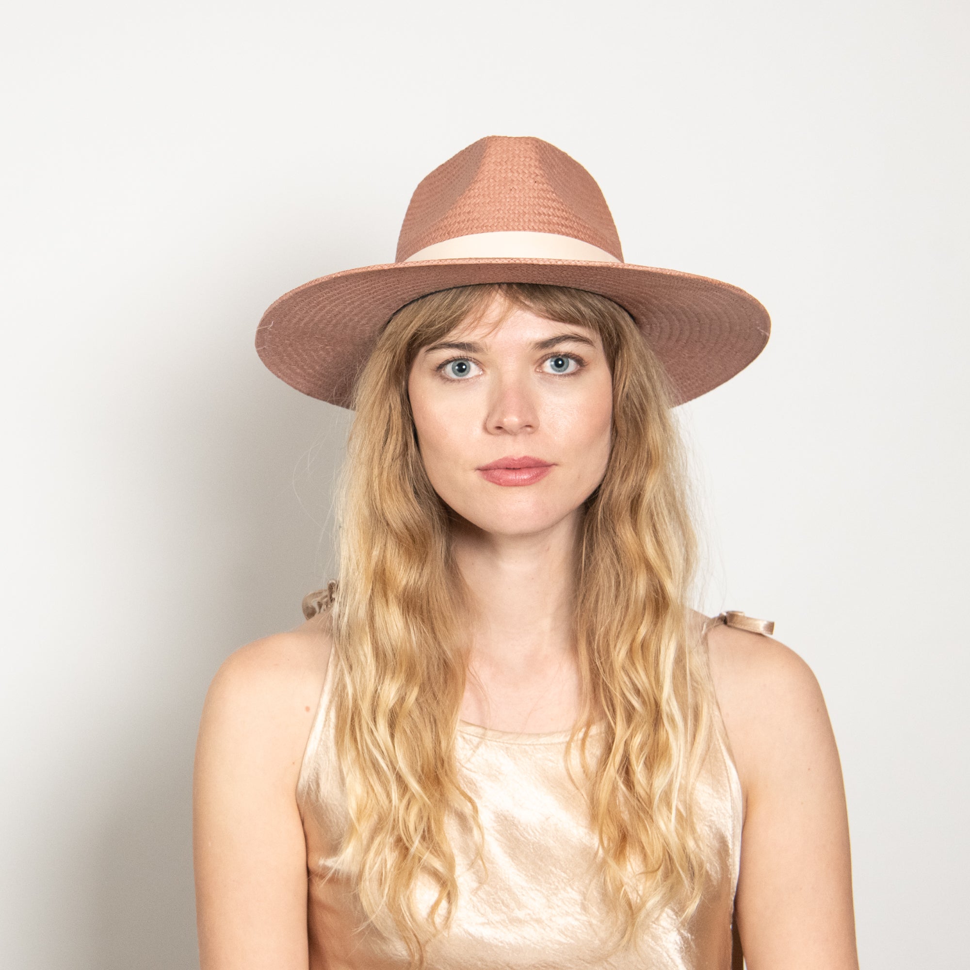 Woman wearing a brown hat against a plain background