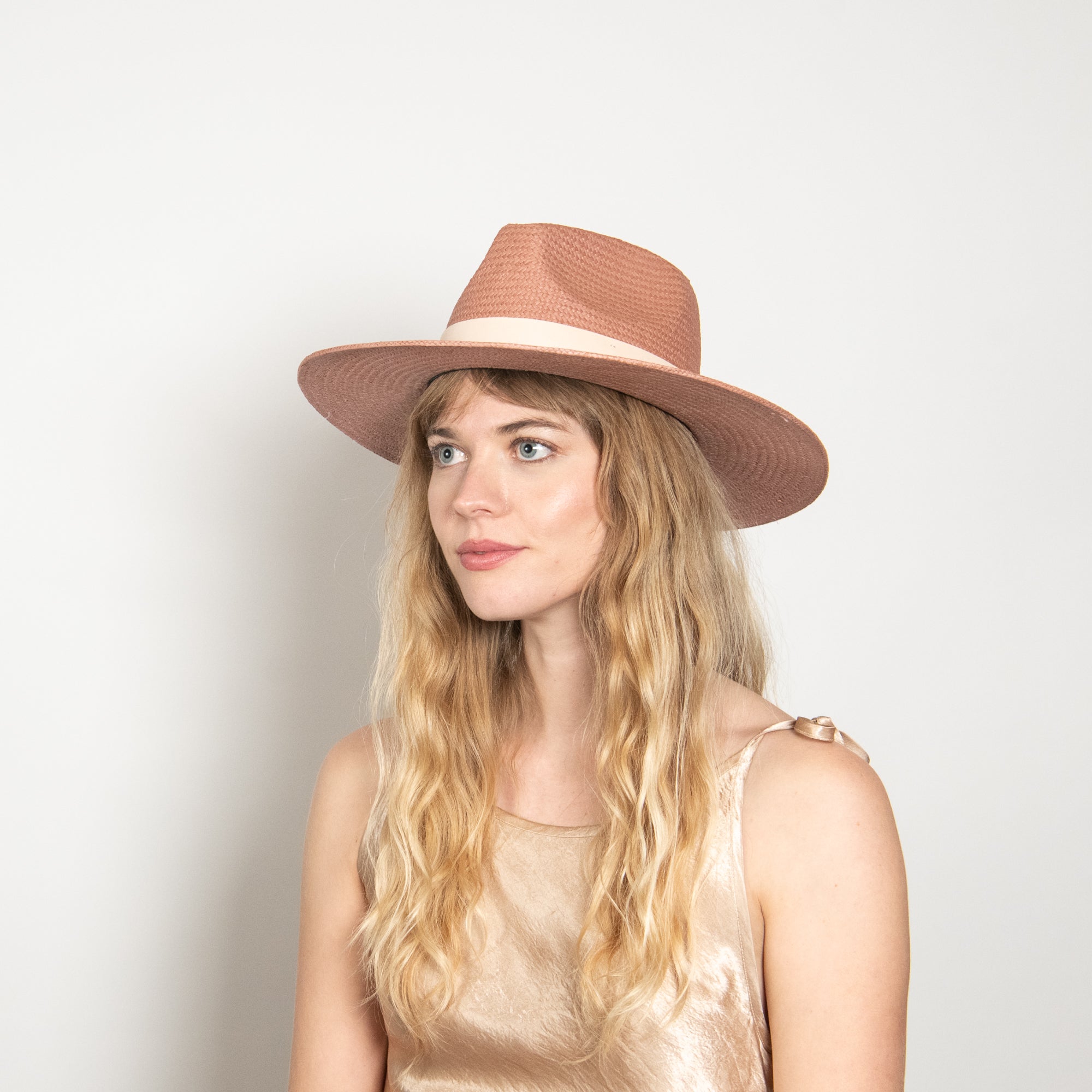 Woman wearing a brown hat against a plain background