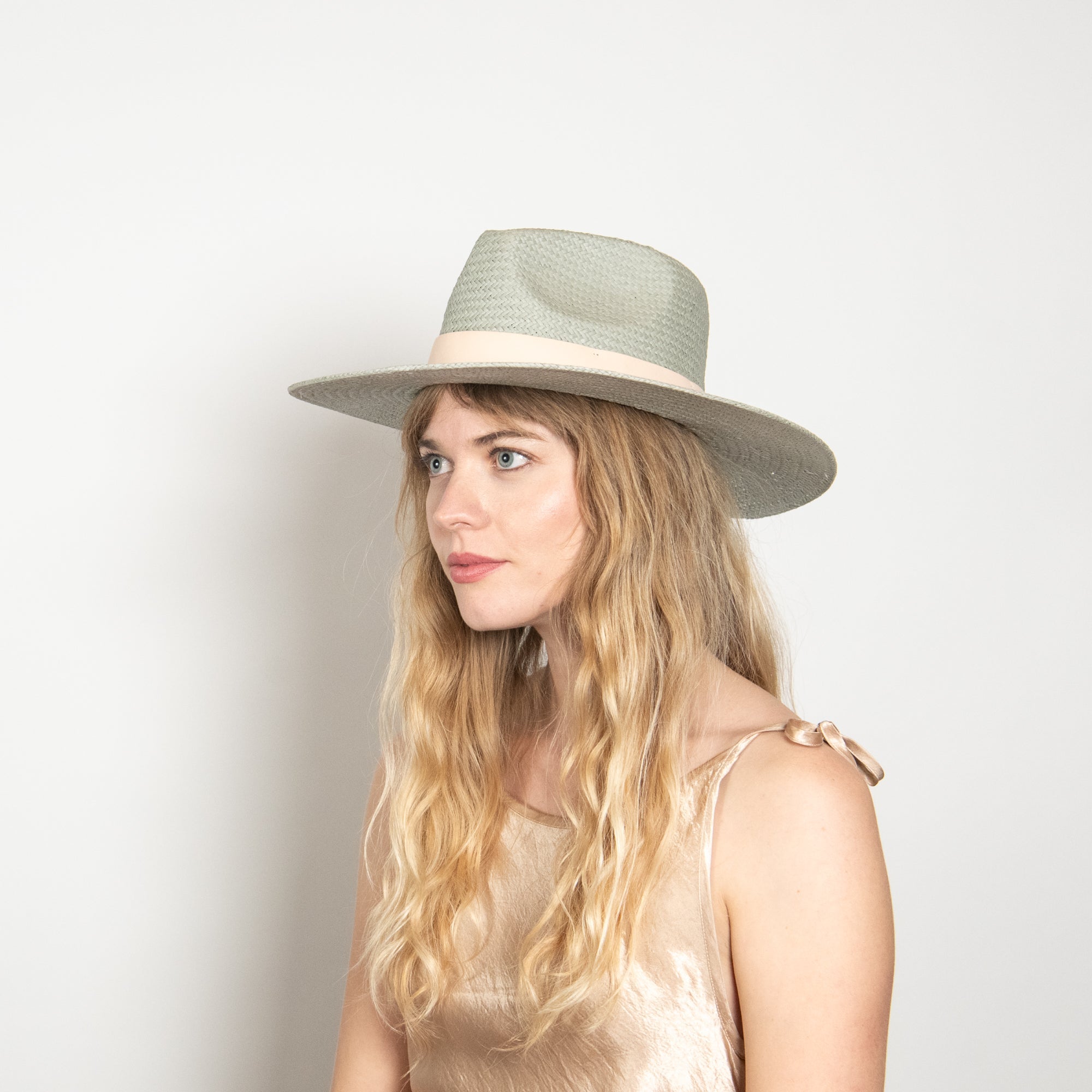Woman wearing a light-colored hat against a plain background