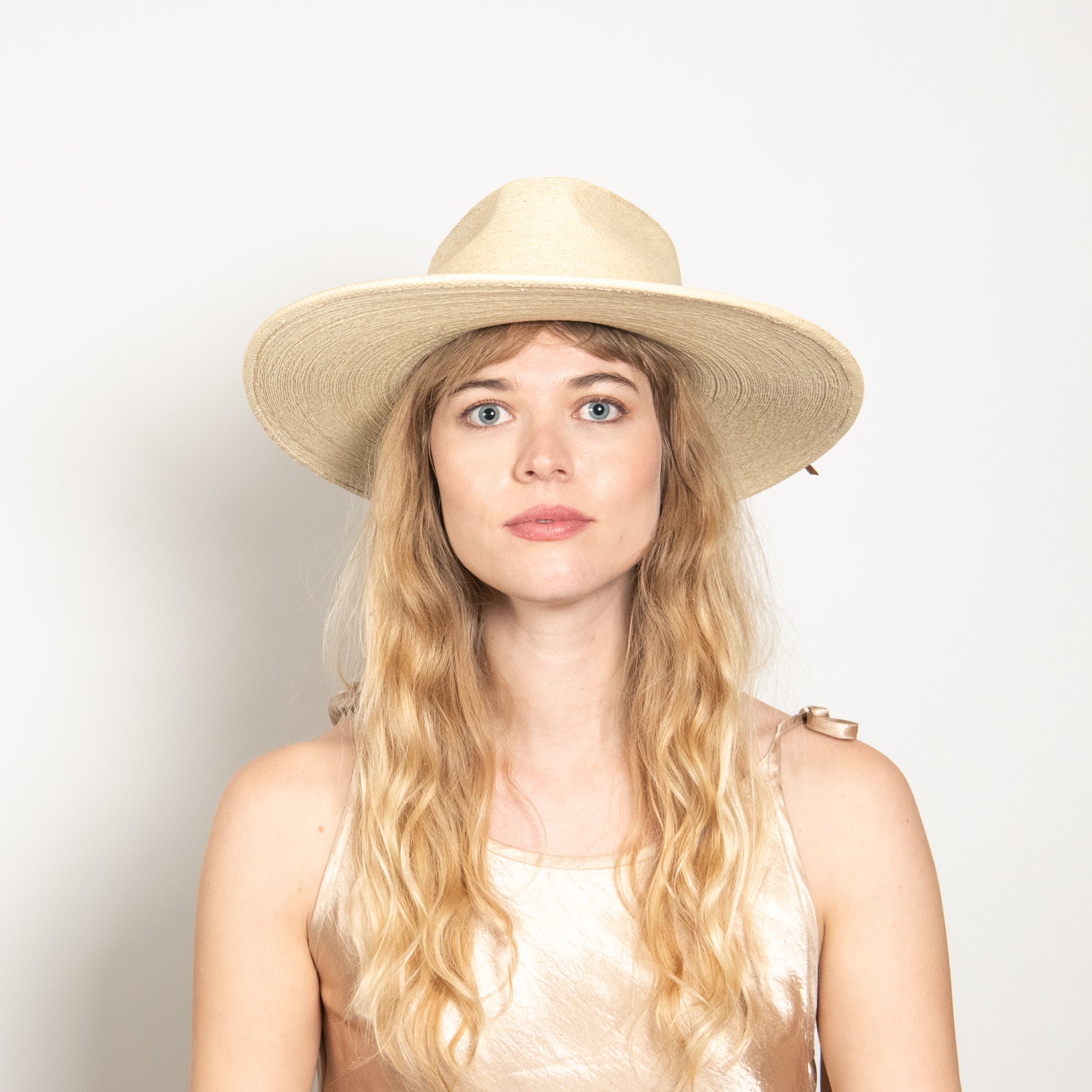 Woman wearing a beige hat against a plain background