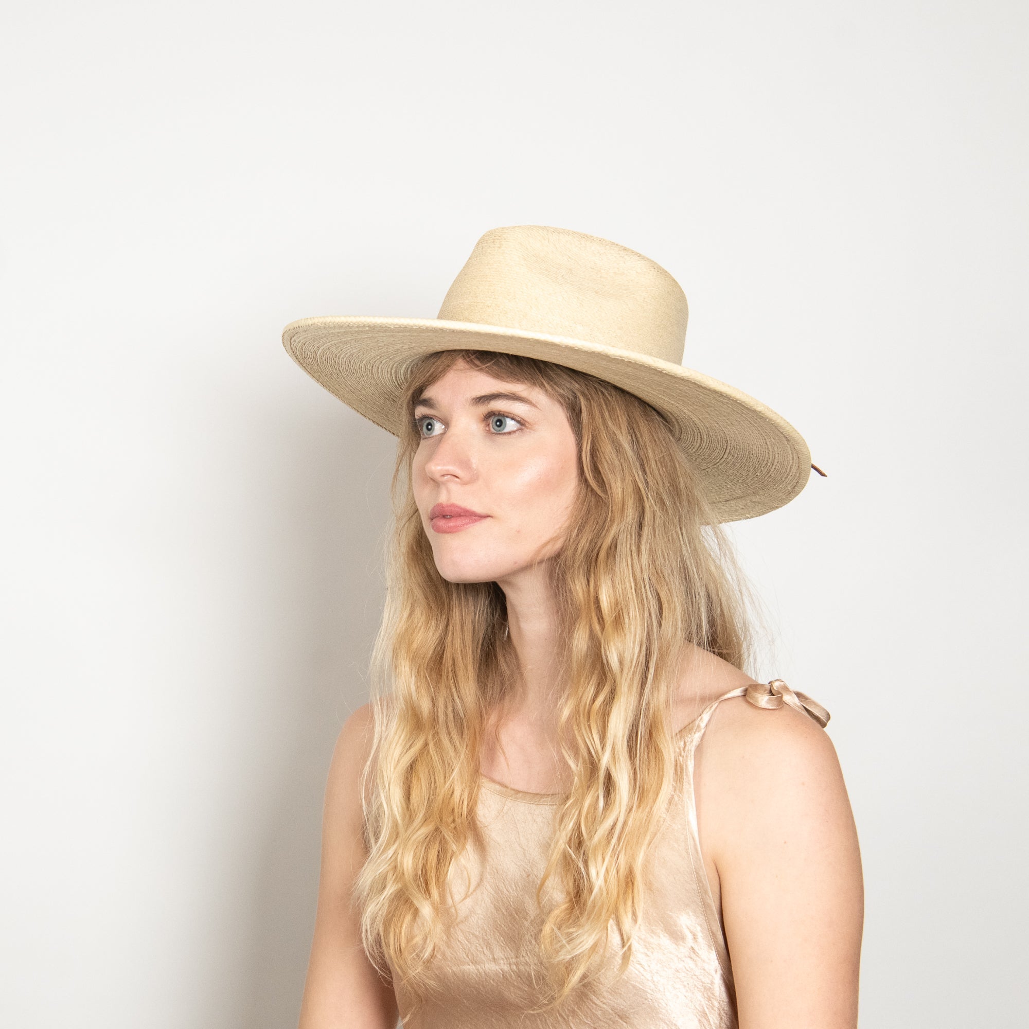 Woman wearing a beige hat against a light background