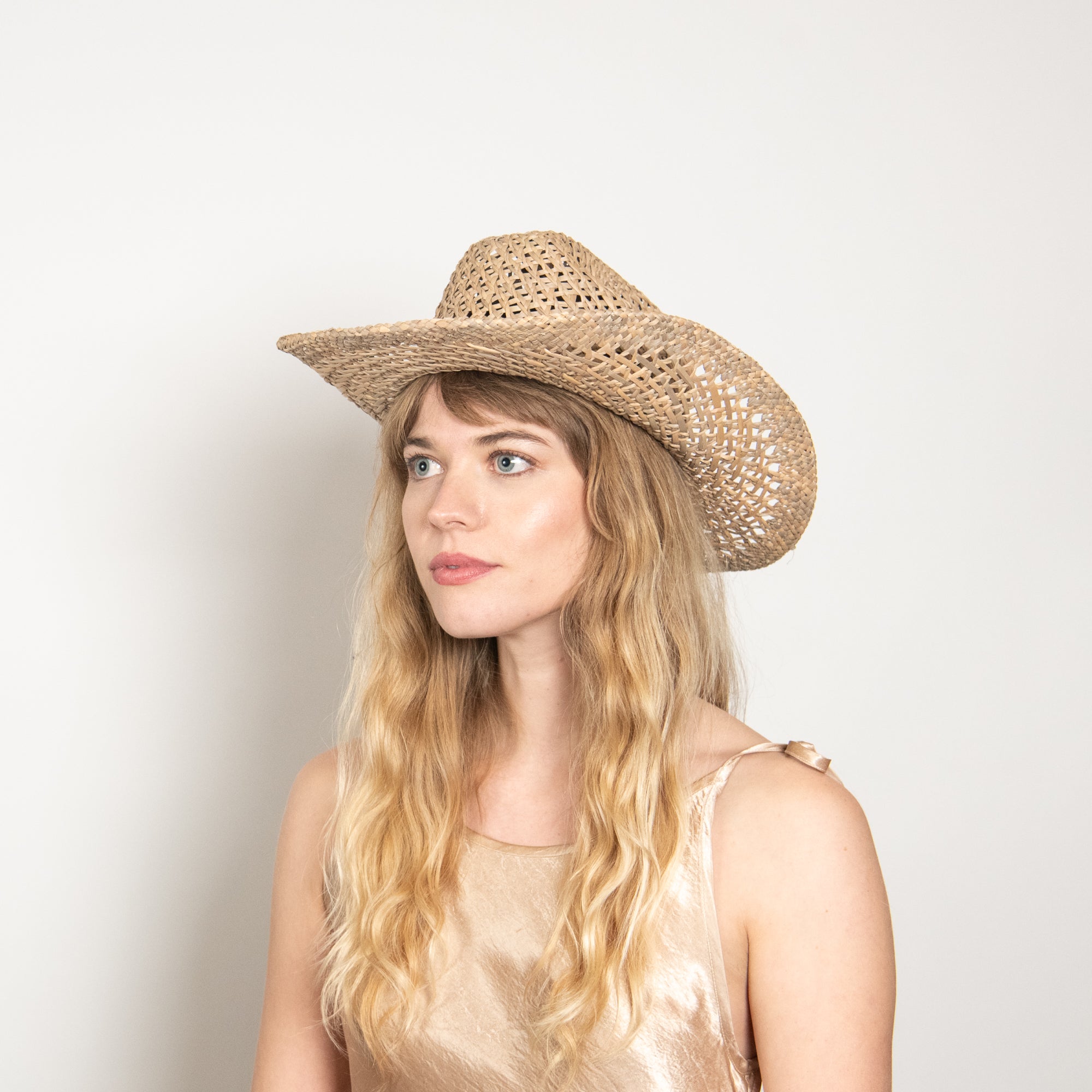 Woman wearing a straw cowboy hat against a plain background
