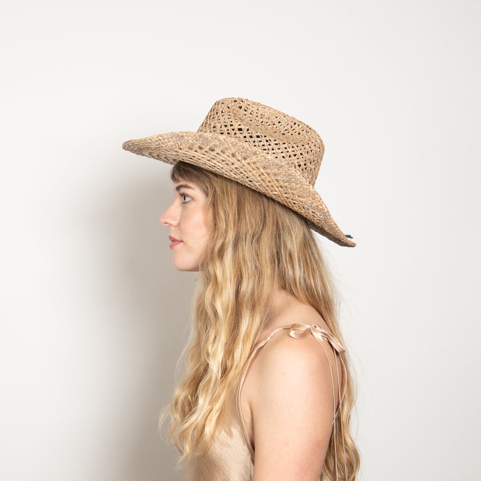 Woman wearing a straw hat against a plain background
