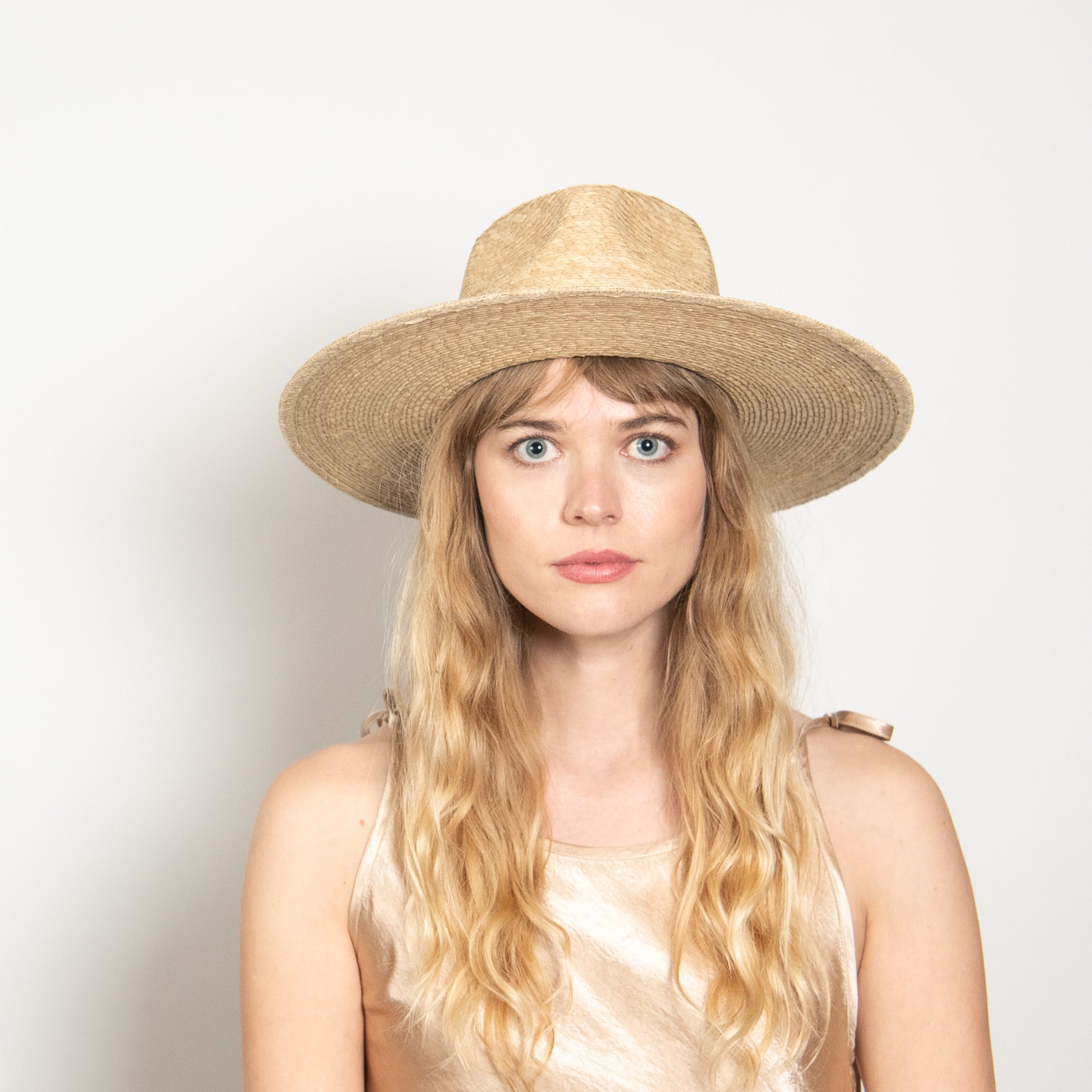 Woman wearing a straw hat against a plain background