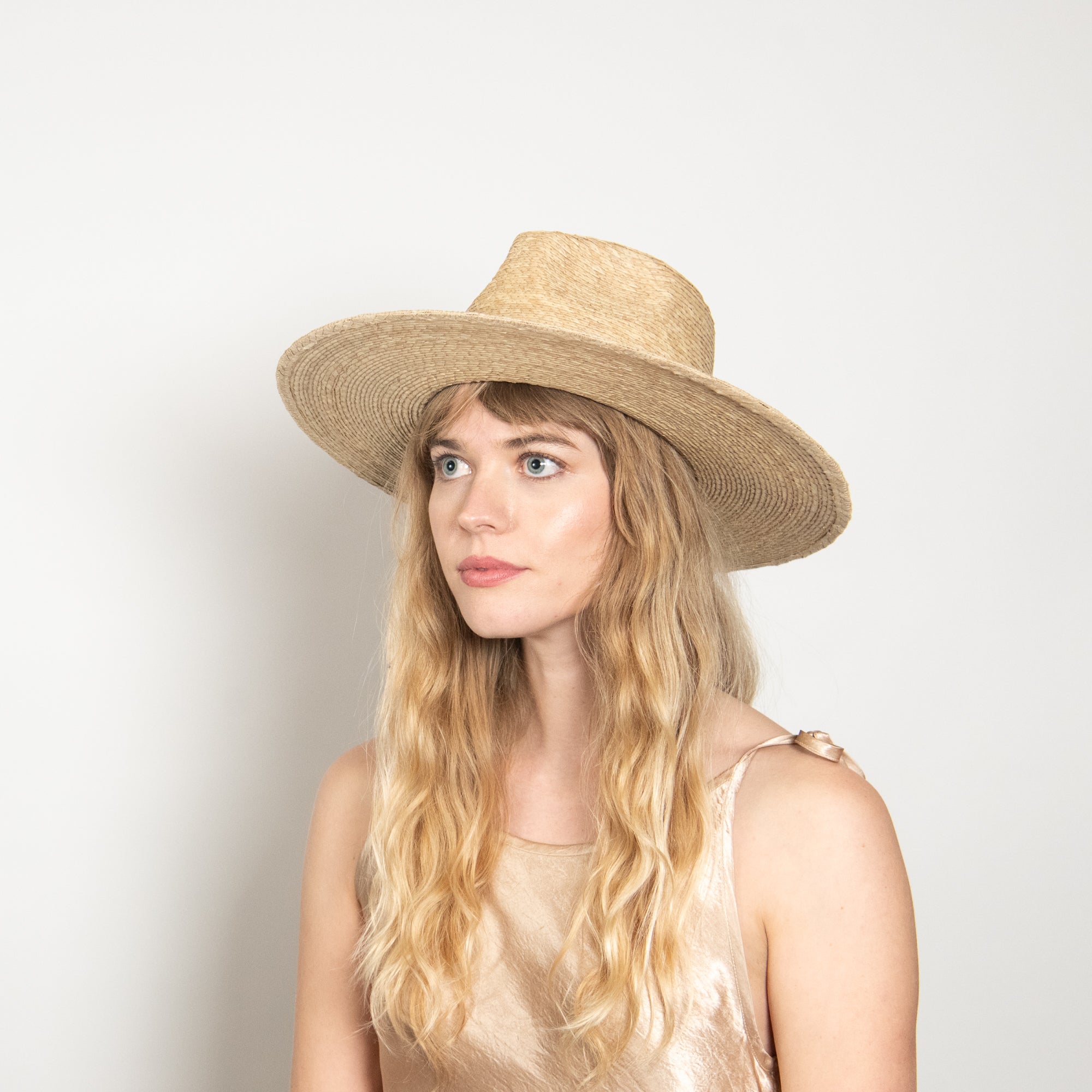 Woman wearing a straw hat against a plain background