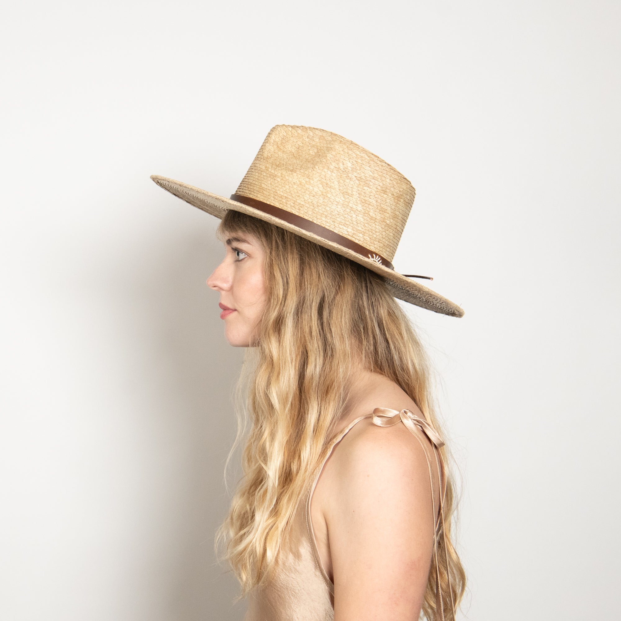 Woman wearing a straw hat against a plain background