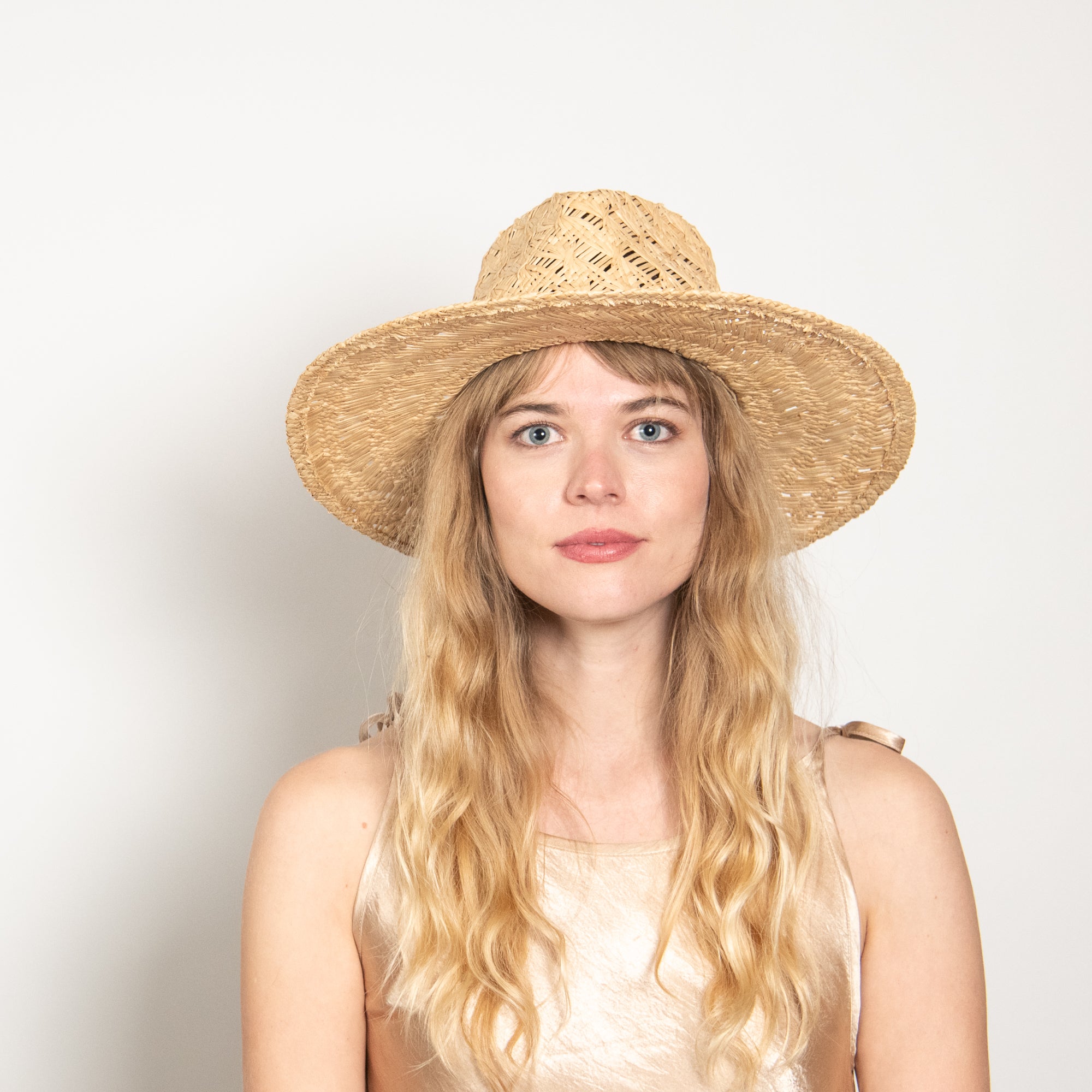 Woman wearing a straw hat against a plain background