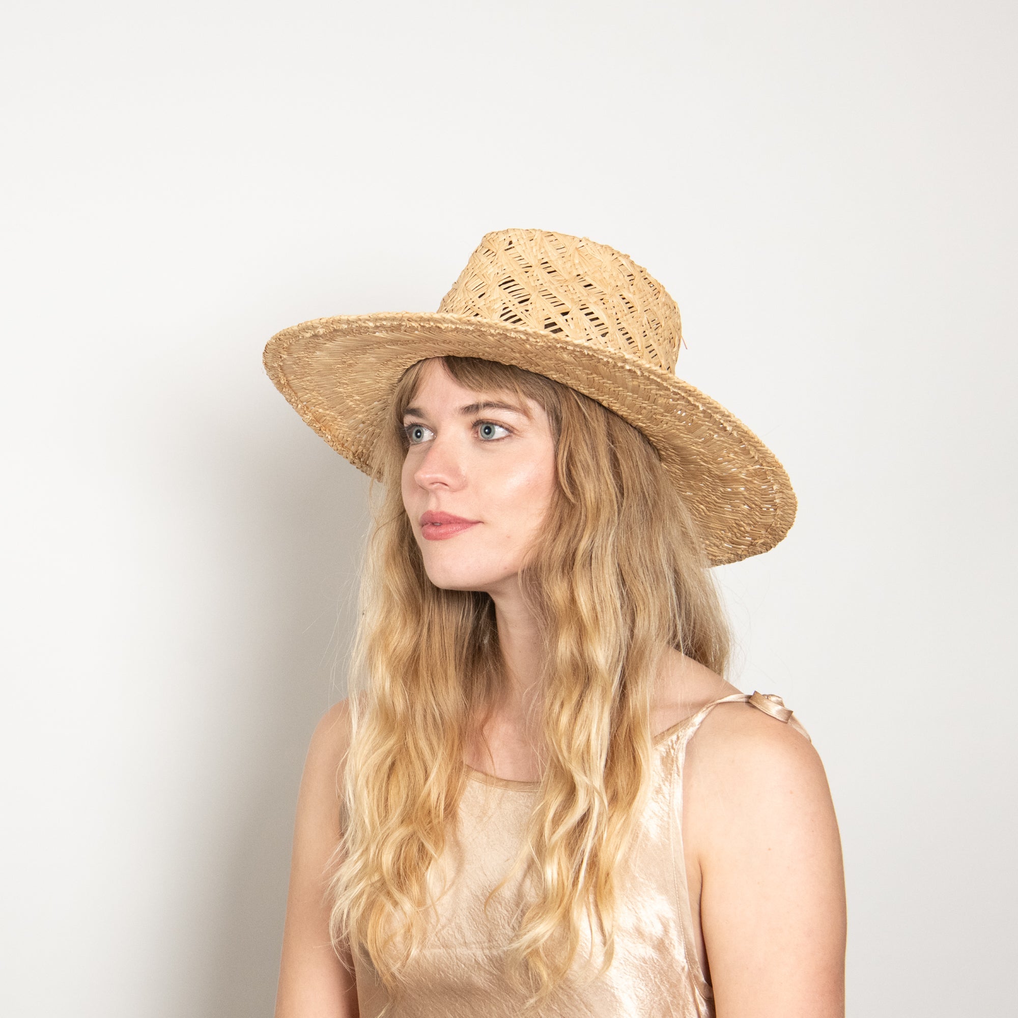 Woman wearing a straw hat against a plain background