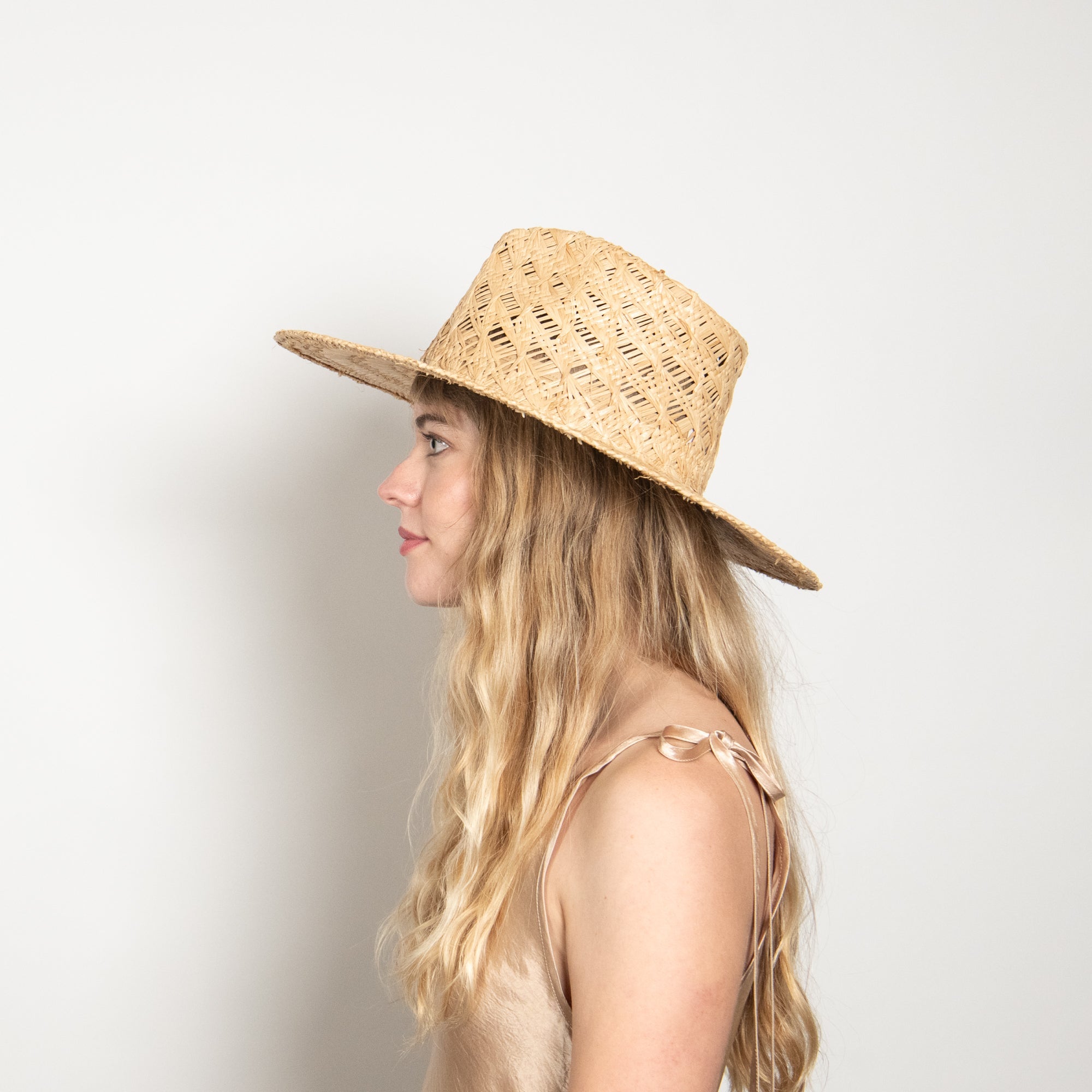 Woman wearing a straw hat against a plain background